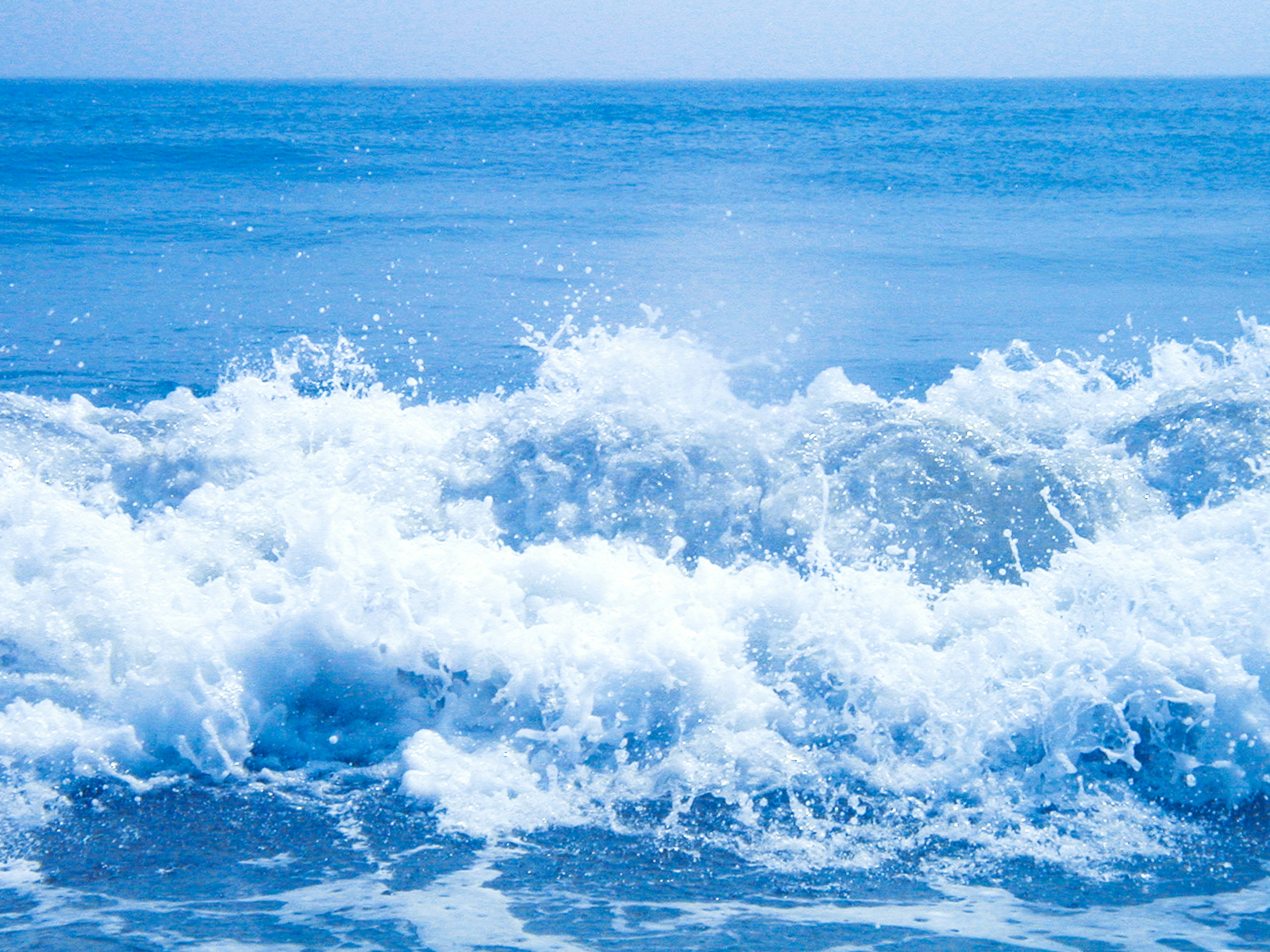 Vagues océaniques bleues s'écrasant sur le rivage