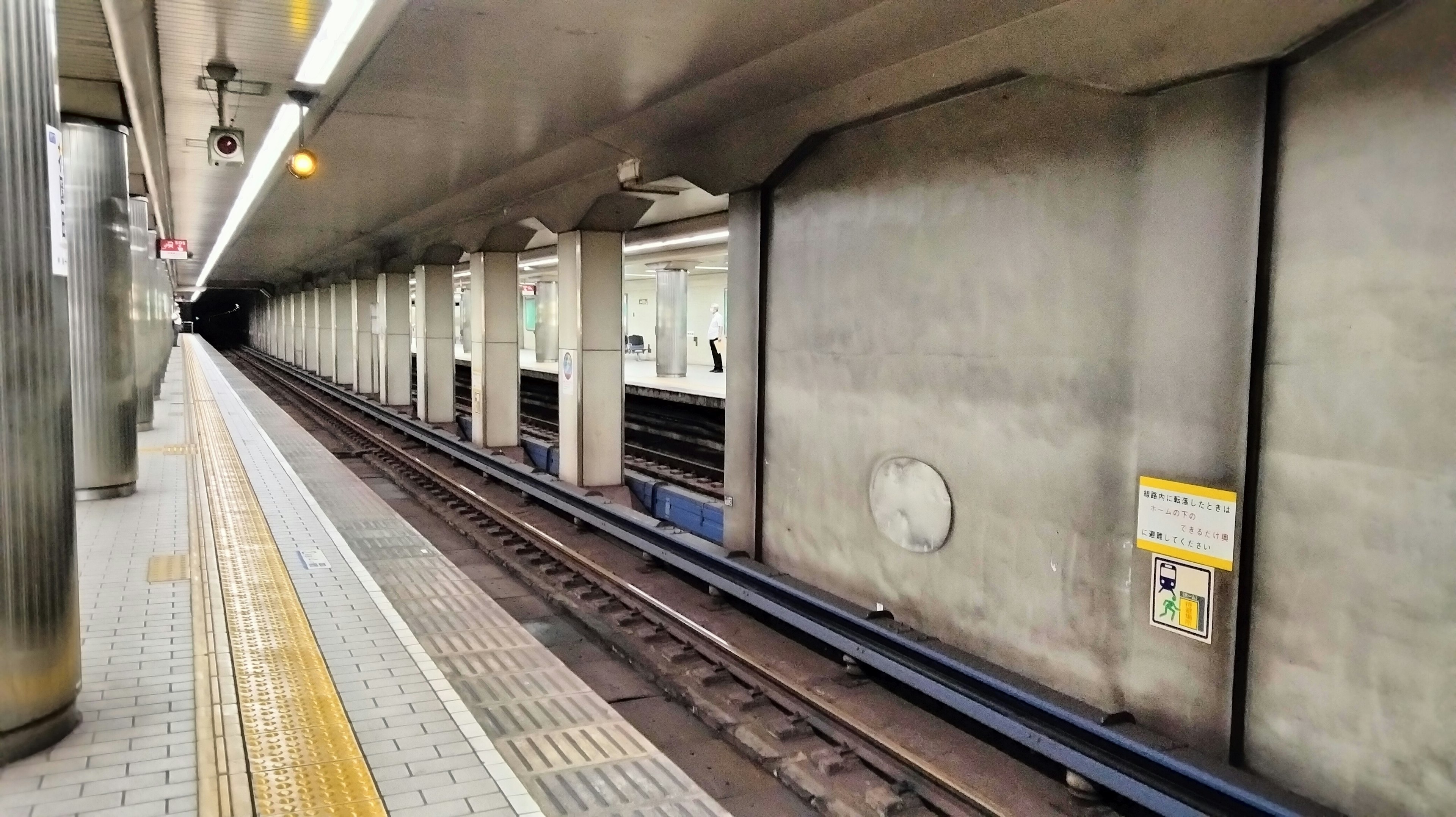 Plateforme de station de métro avec des murs en béton et des rails visibles