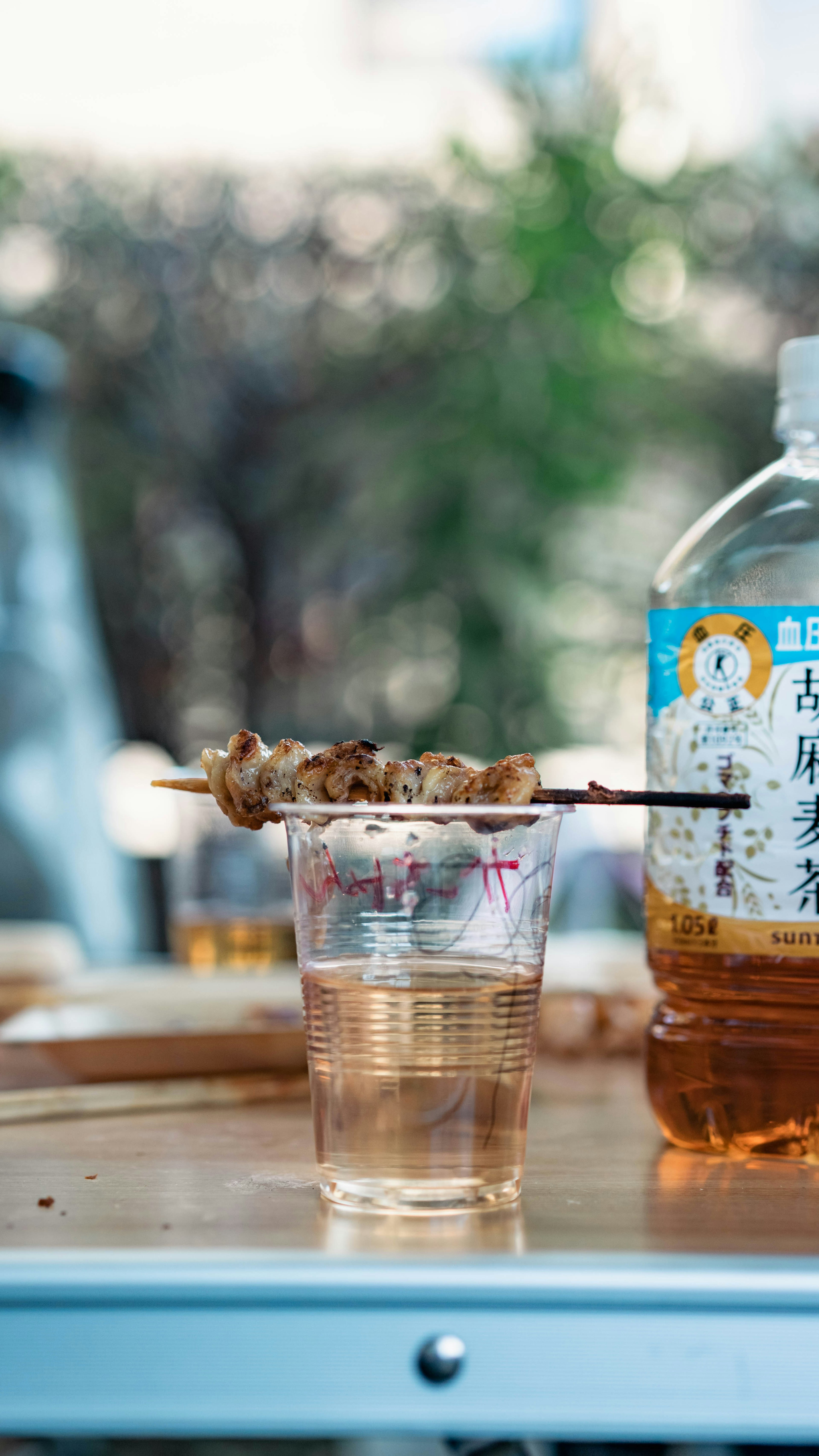 Image of skewered grilled chicken resting on a cup with a bottle beside it