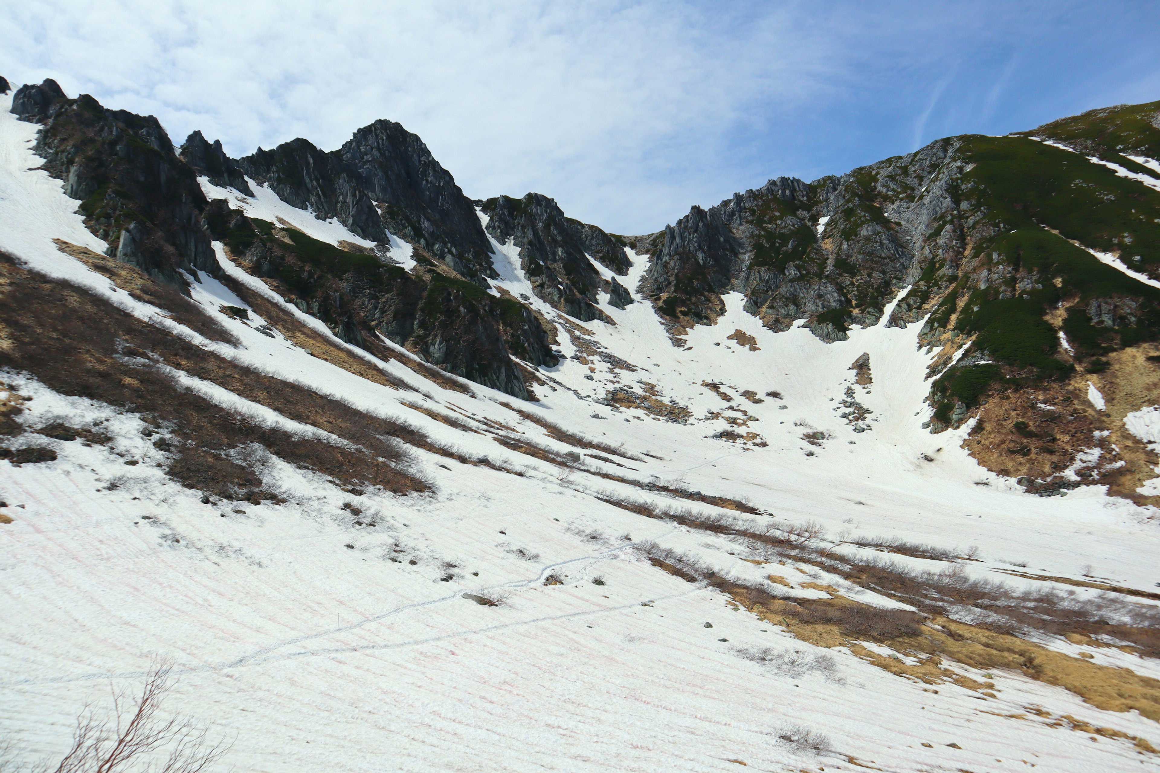 Pendiente de montaña cubierta de nieve con terreno rocoso