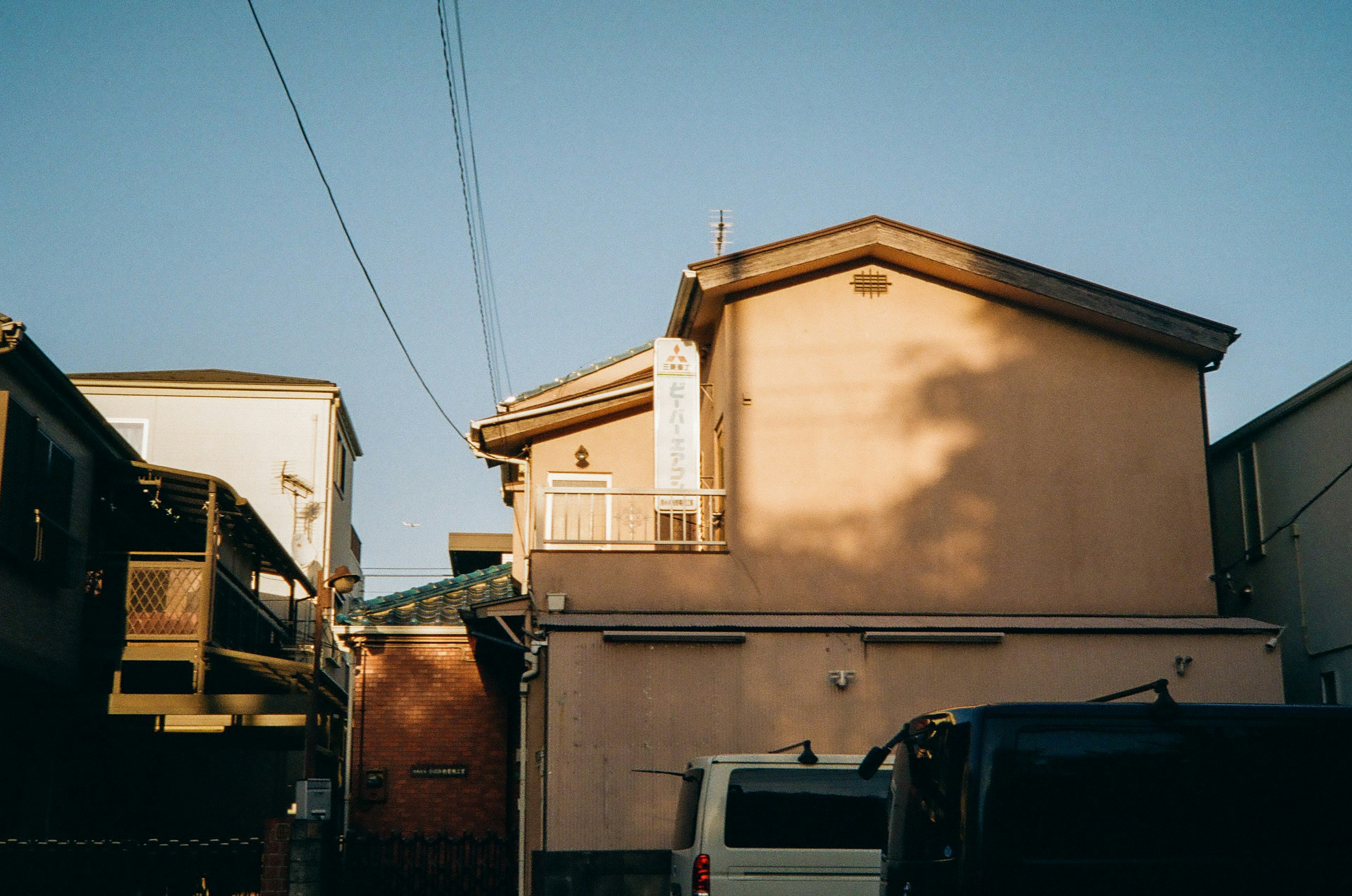 住宅街の一角にある淡い色の家と青空