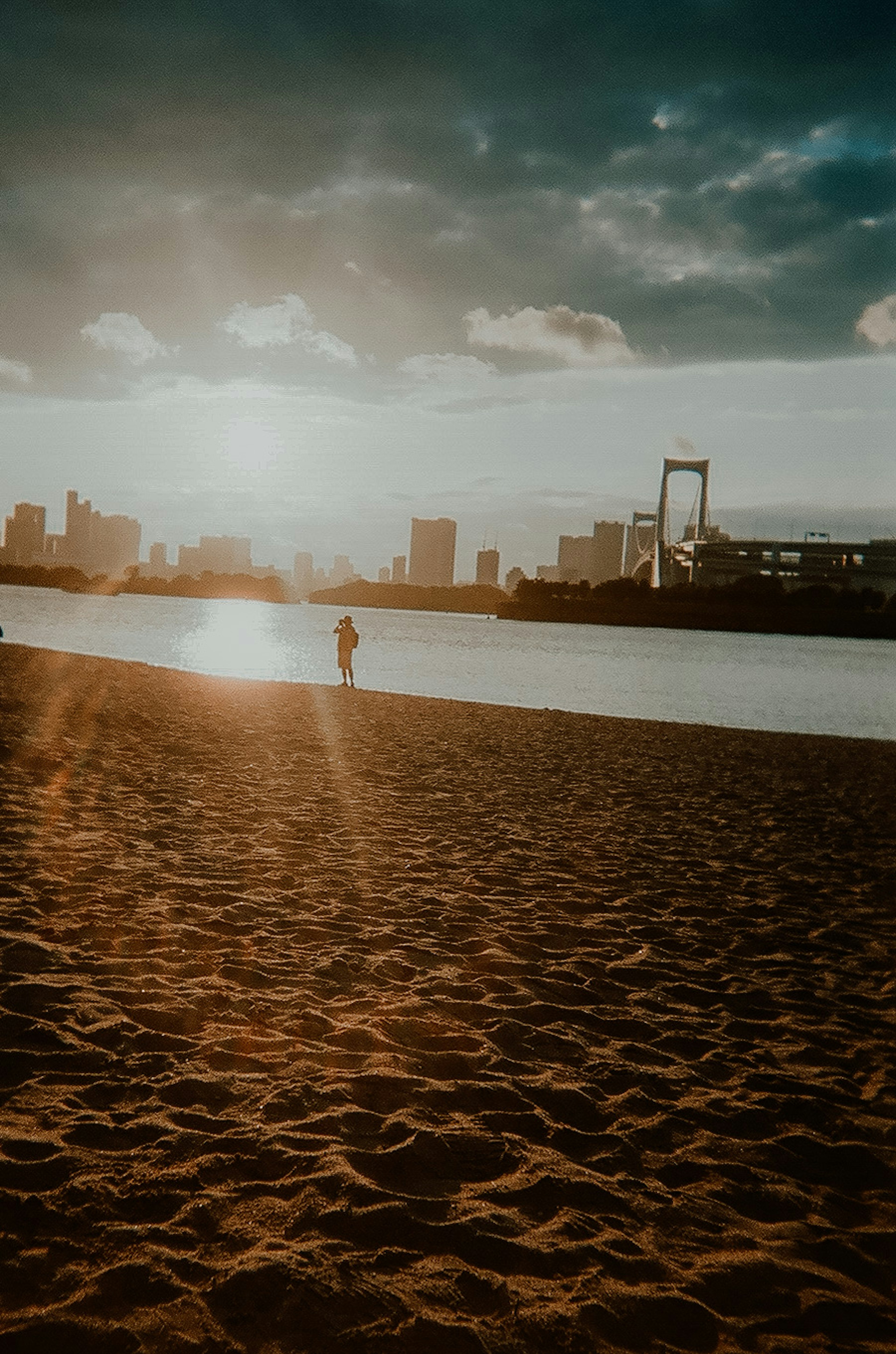 夕日を背景にした砂浜と水面の反射を持つ都市風景