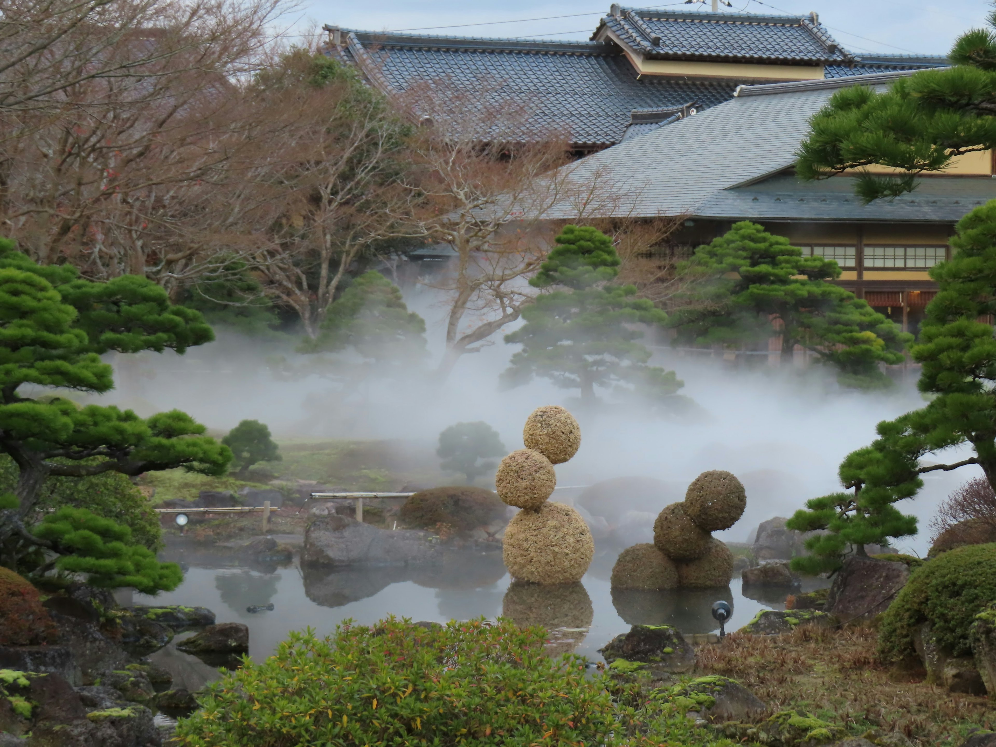 Japanese garden scene with mist and ornamental straw balls in a pond