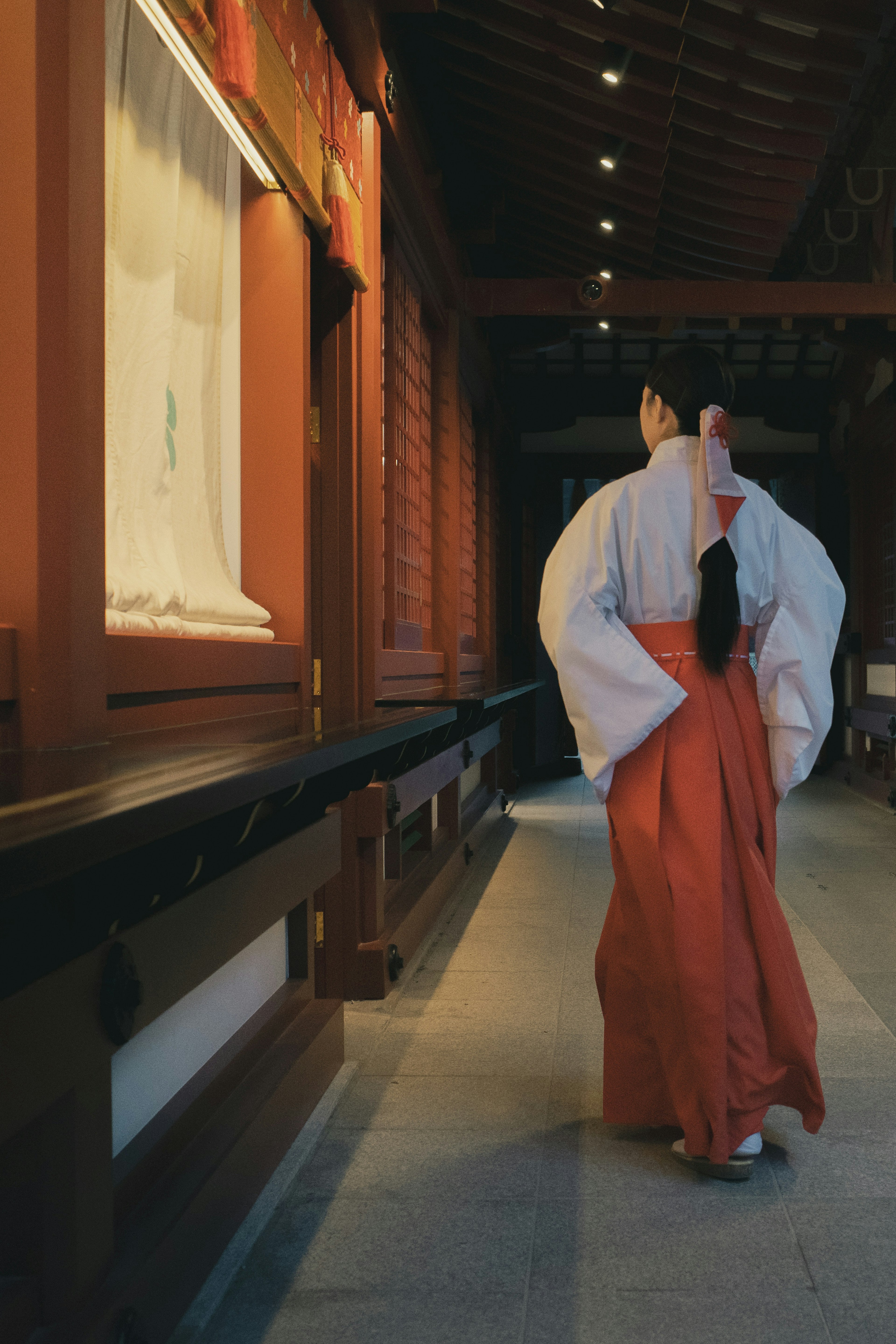 A woman in a red kimono walking down a corridor of a historic building