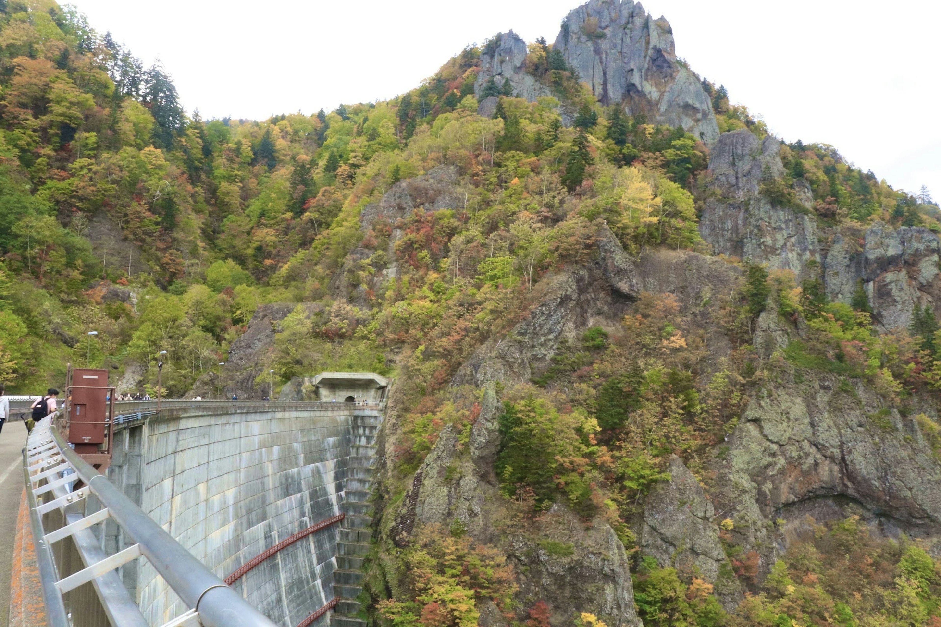 Scenic view of a dam surrounded by mountains with autumn foliage