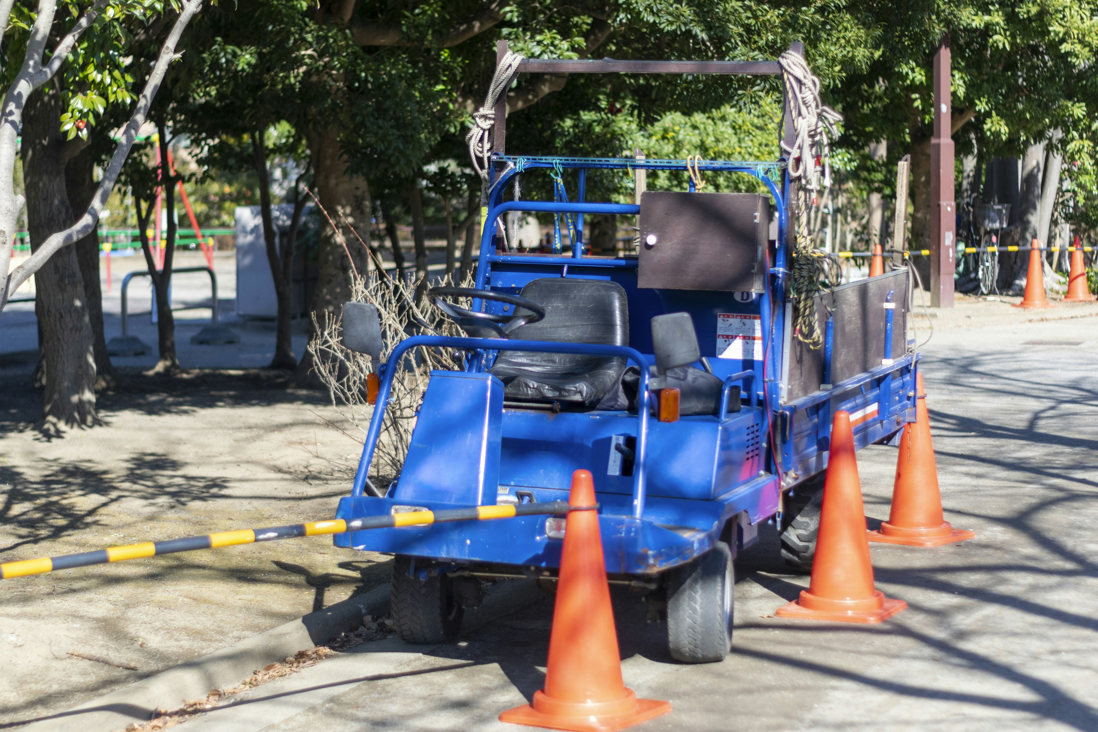 A blue utility vehicle surrounded by orange traffic cones