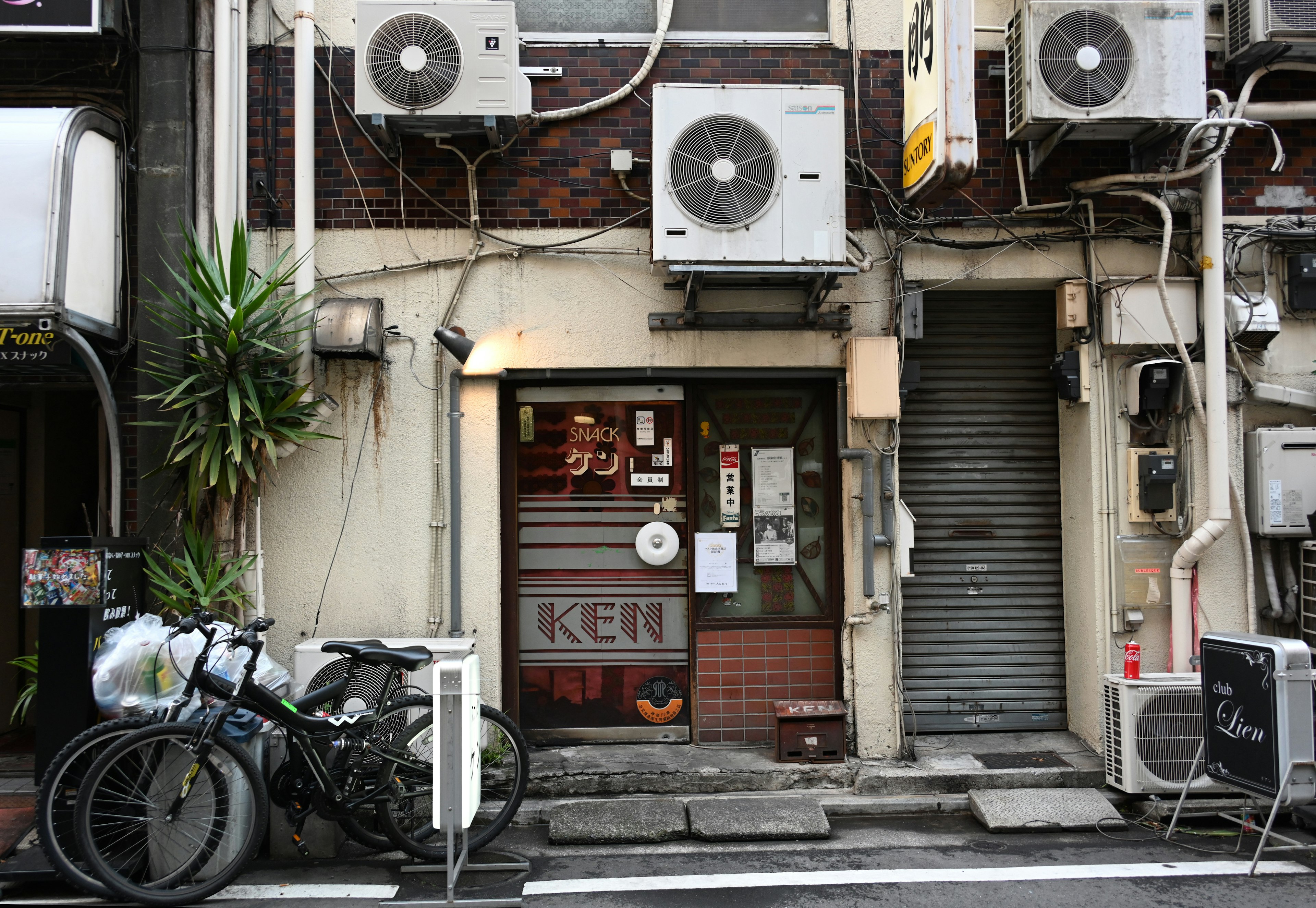 古い建物の外観とエアコンが並ぶ風景 自転車が置かれた入口