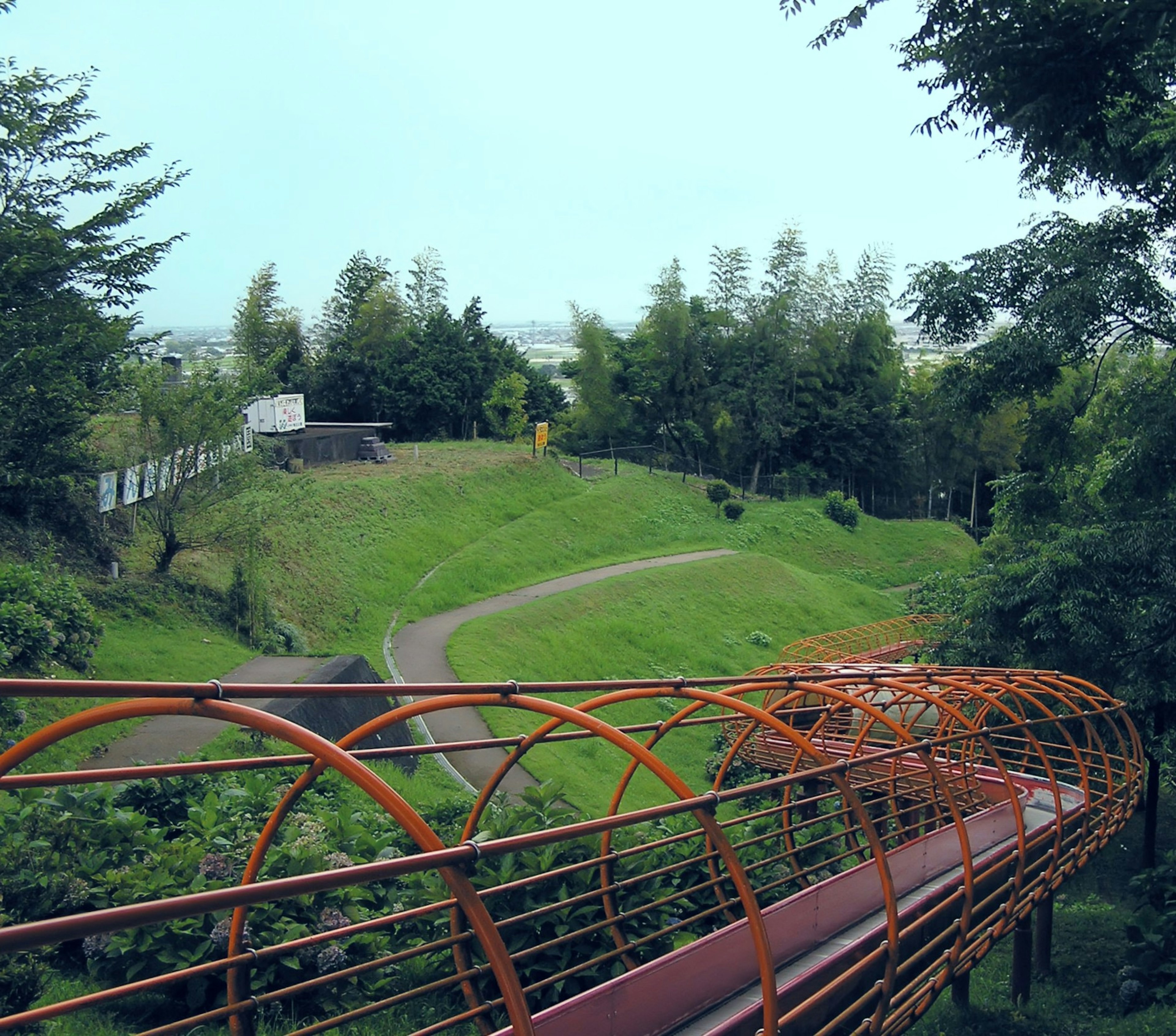 Vista panoramica di un parco verde con un ponte arancione a forma di tunnel