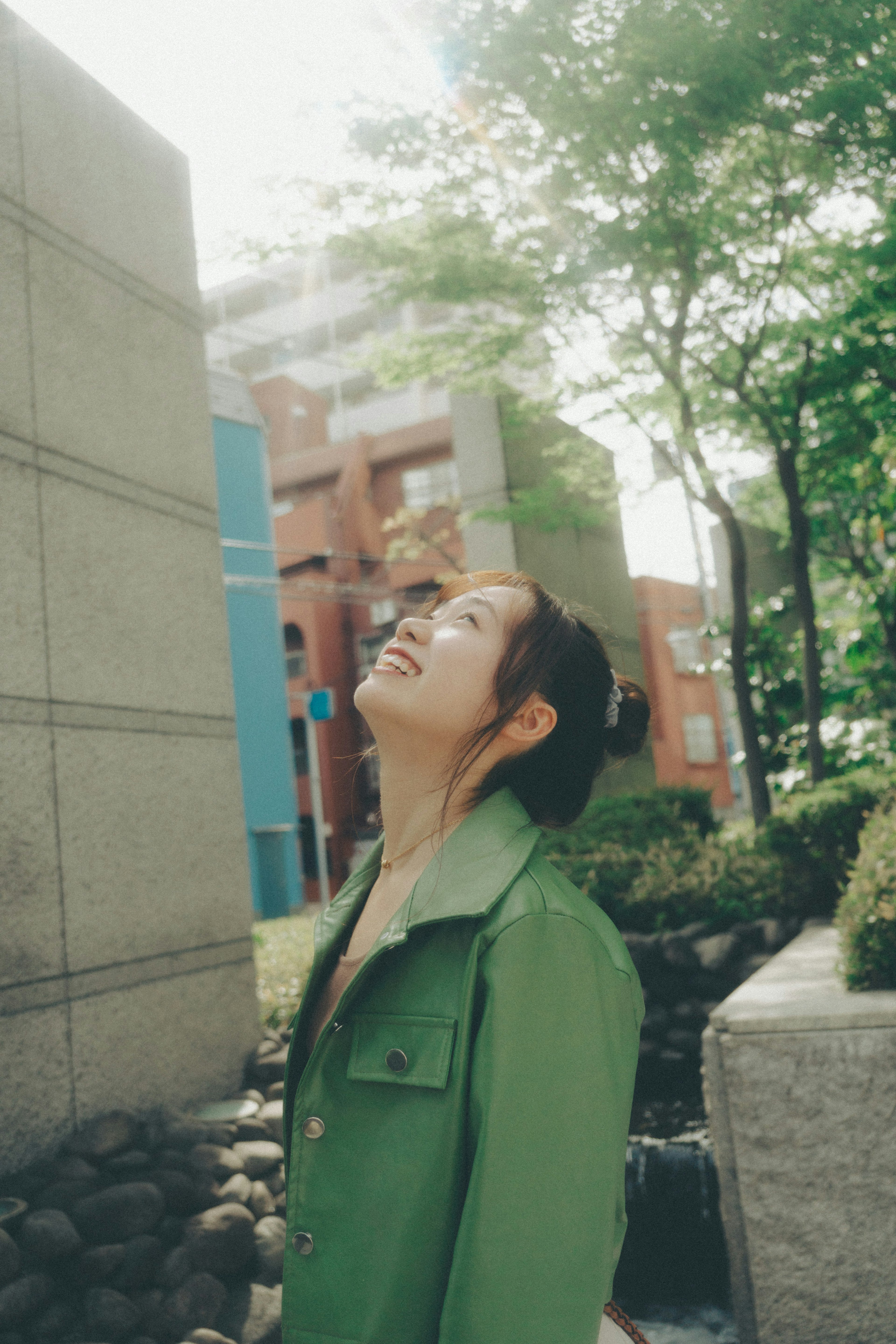 A woman in a green jacket looking up at the sky