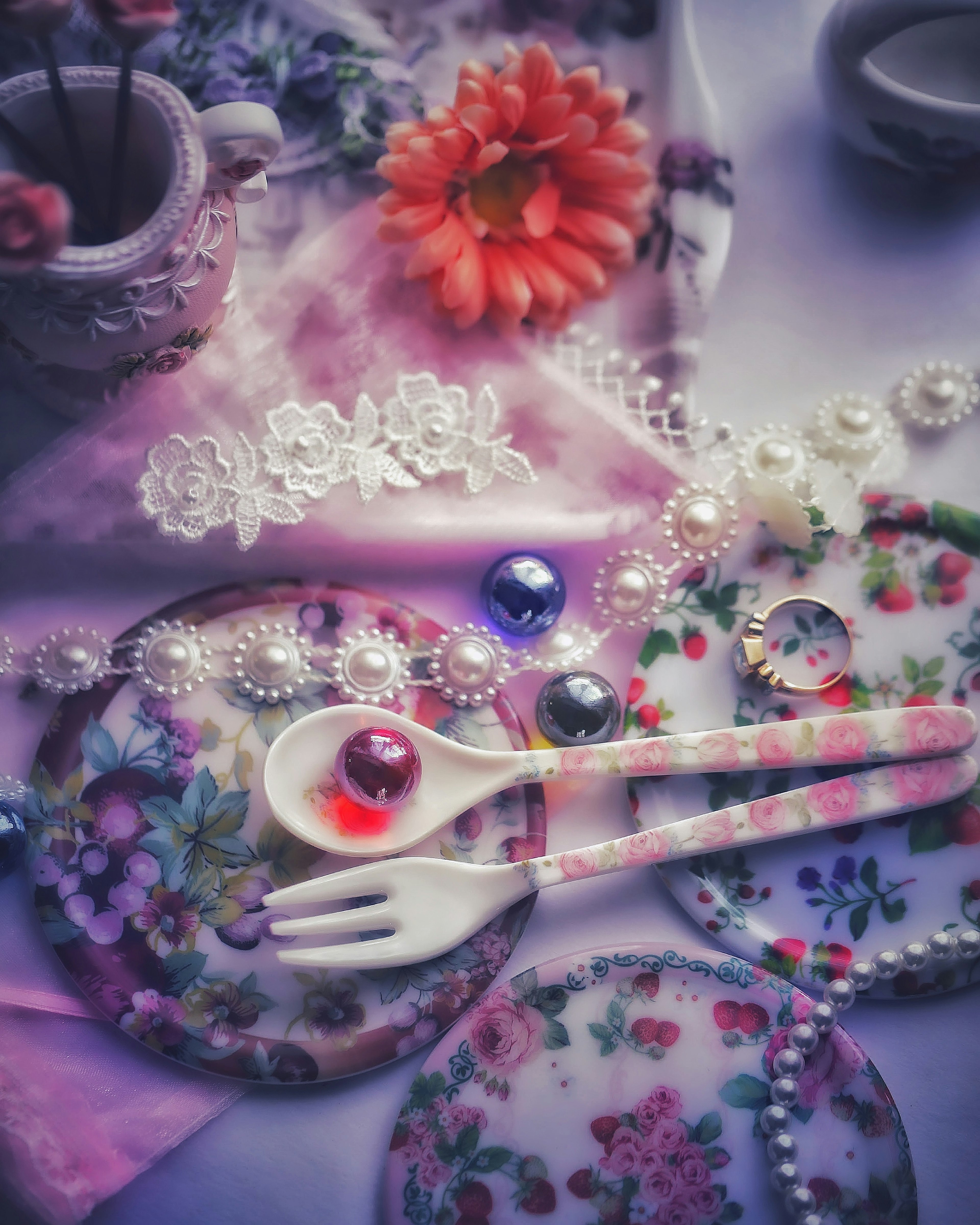 Assiette florale colorée et couverts disposés sur une table avec des fleurs et des accessoires en perles