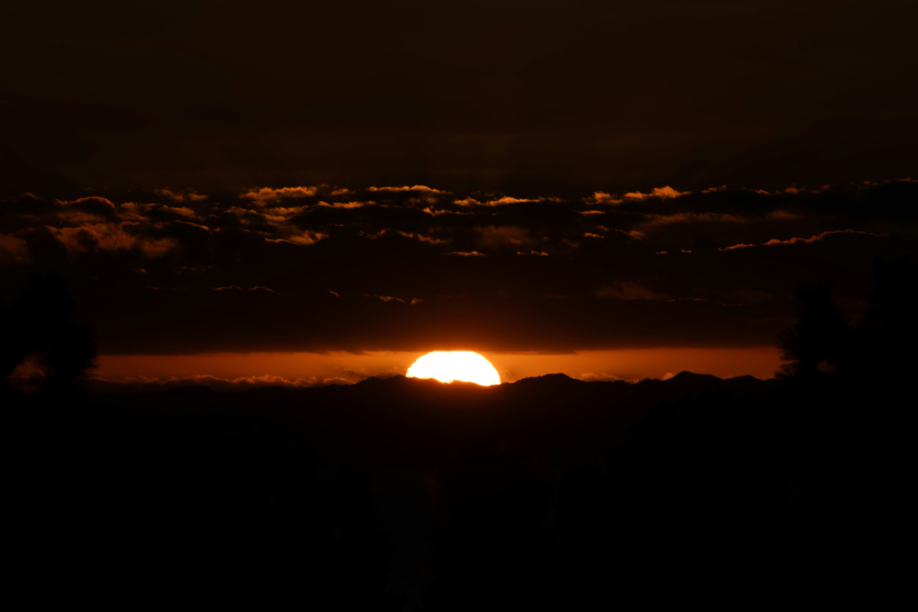 夕日が地平線に沈む美しい風景 暗い雲に囲まれたオレンジ色の光