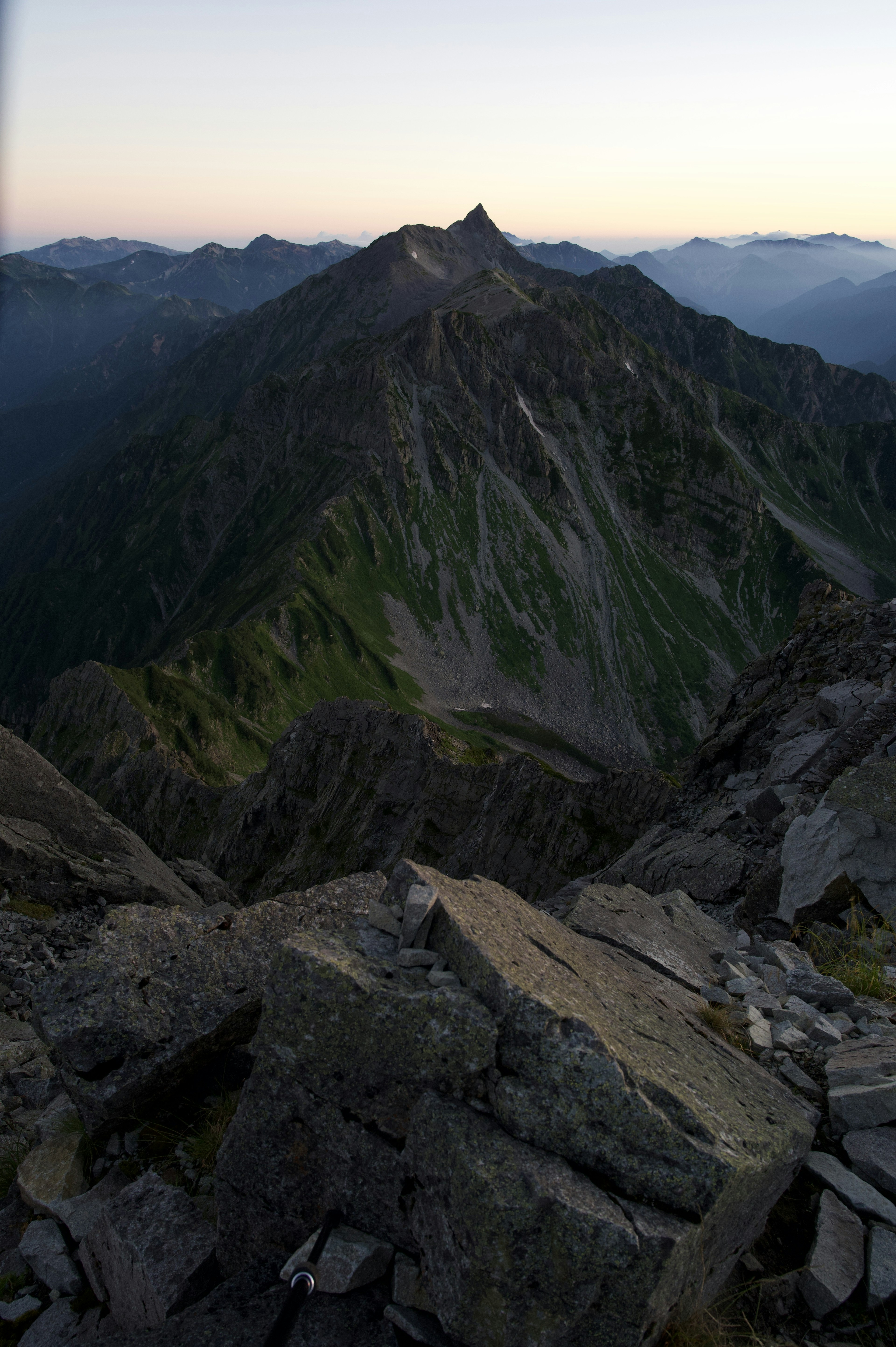 Vue panoramique depuis un sommet montagneux terrain rocheux lumière douce du soir sommets lointains