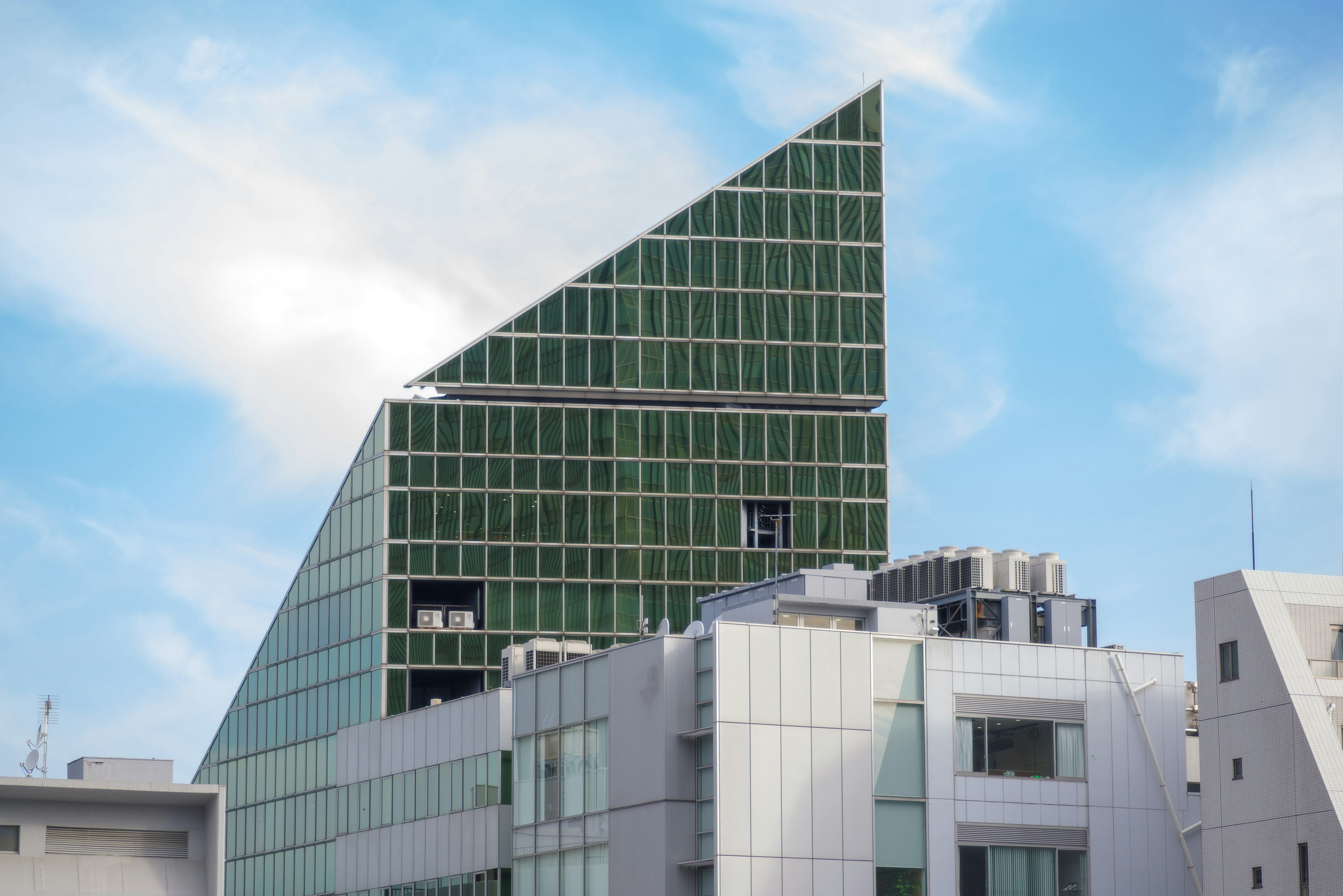 Edificio moderno con techo triangular de vidrio y fachada verde