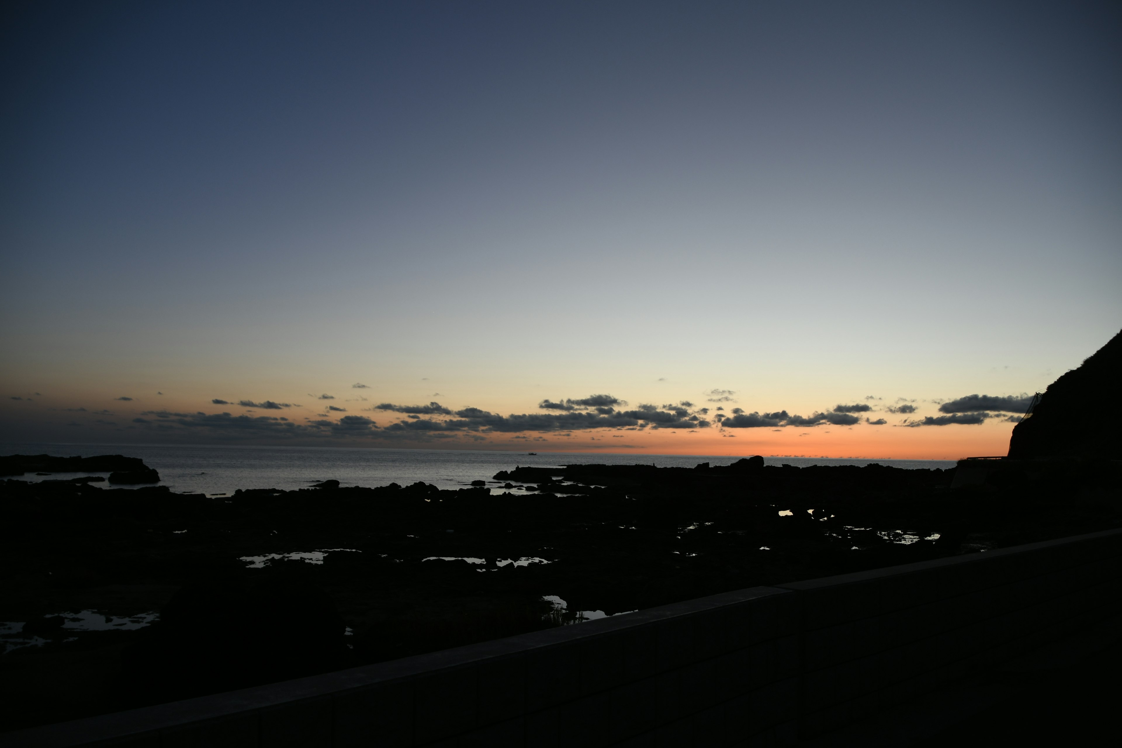 Coastal sunset with calm waves and distant clouds