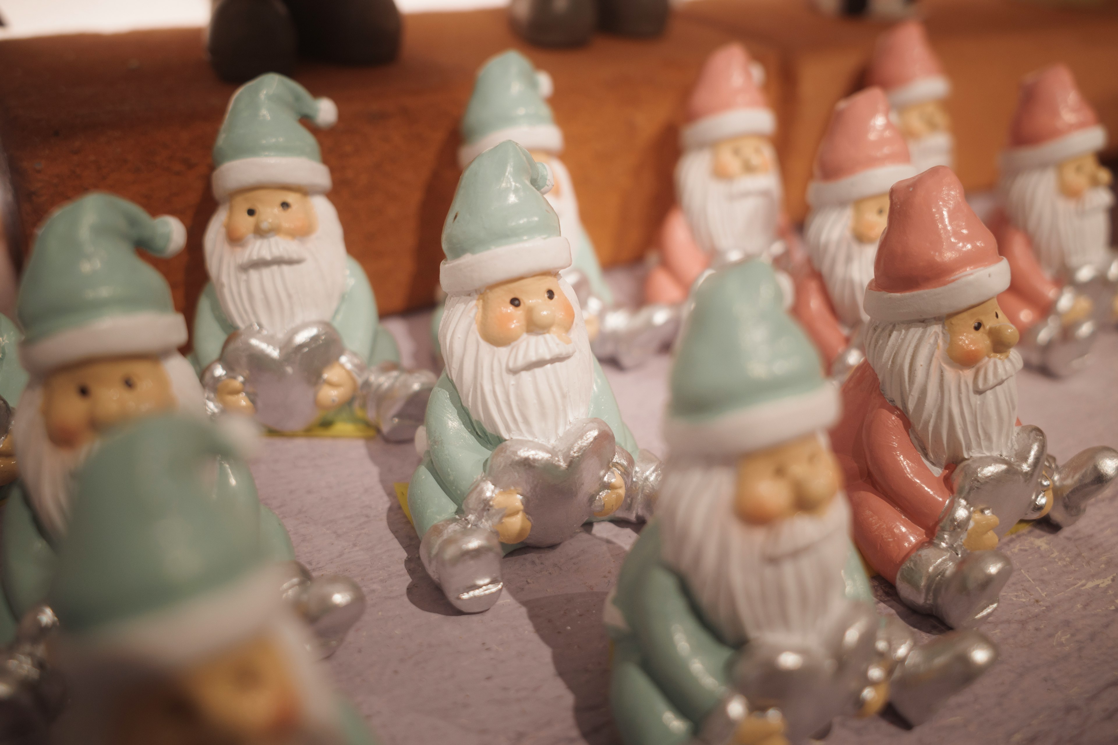 Une collection de figurines de Père Noël avec des chapeaux teal et rose disposées en rangées