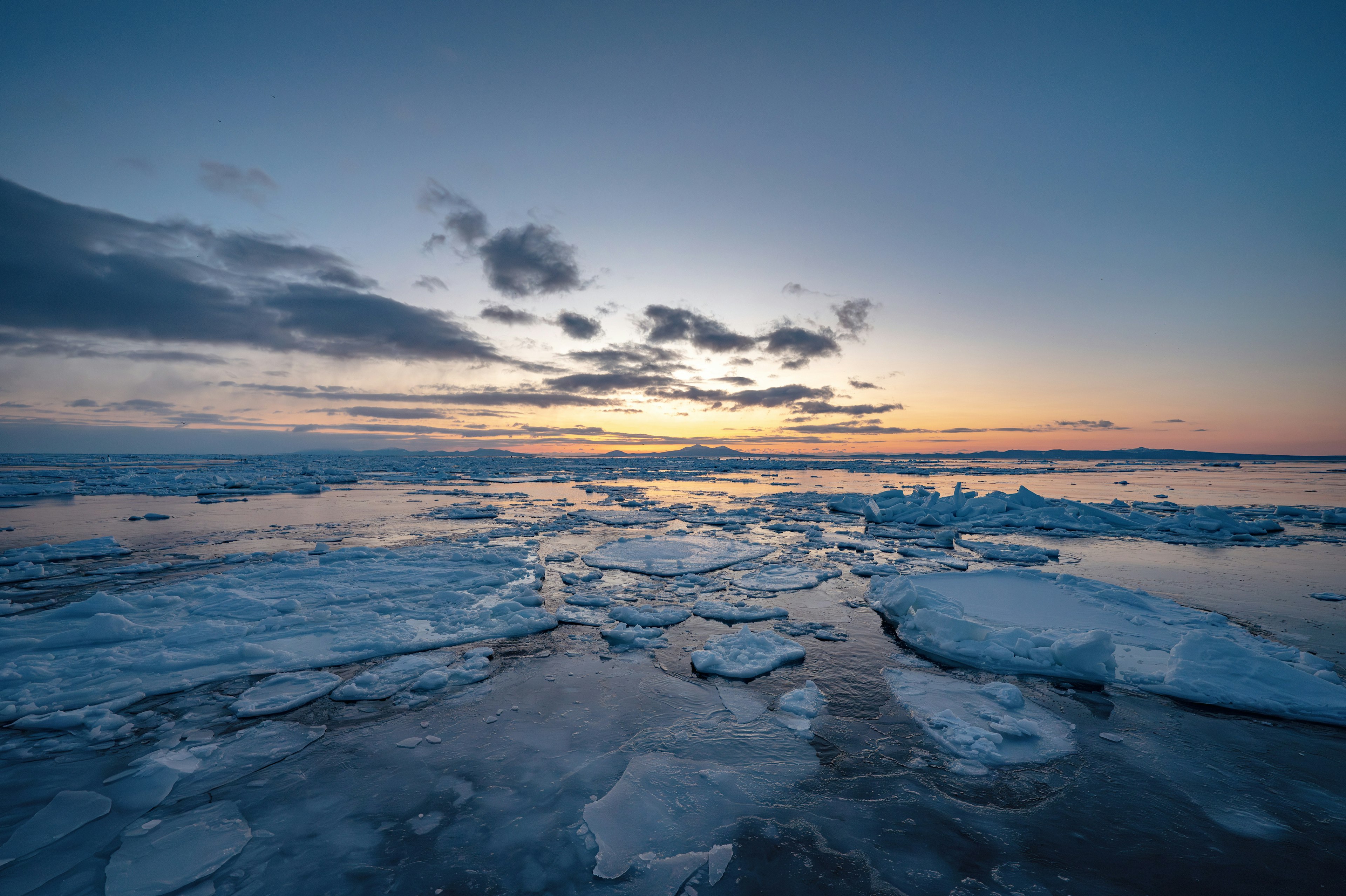 Sea with floating ice chunks and sunset sky