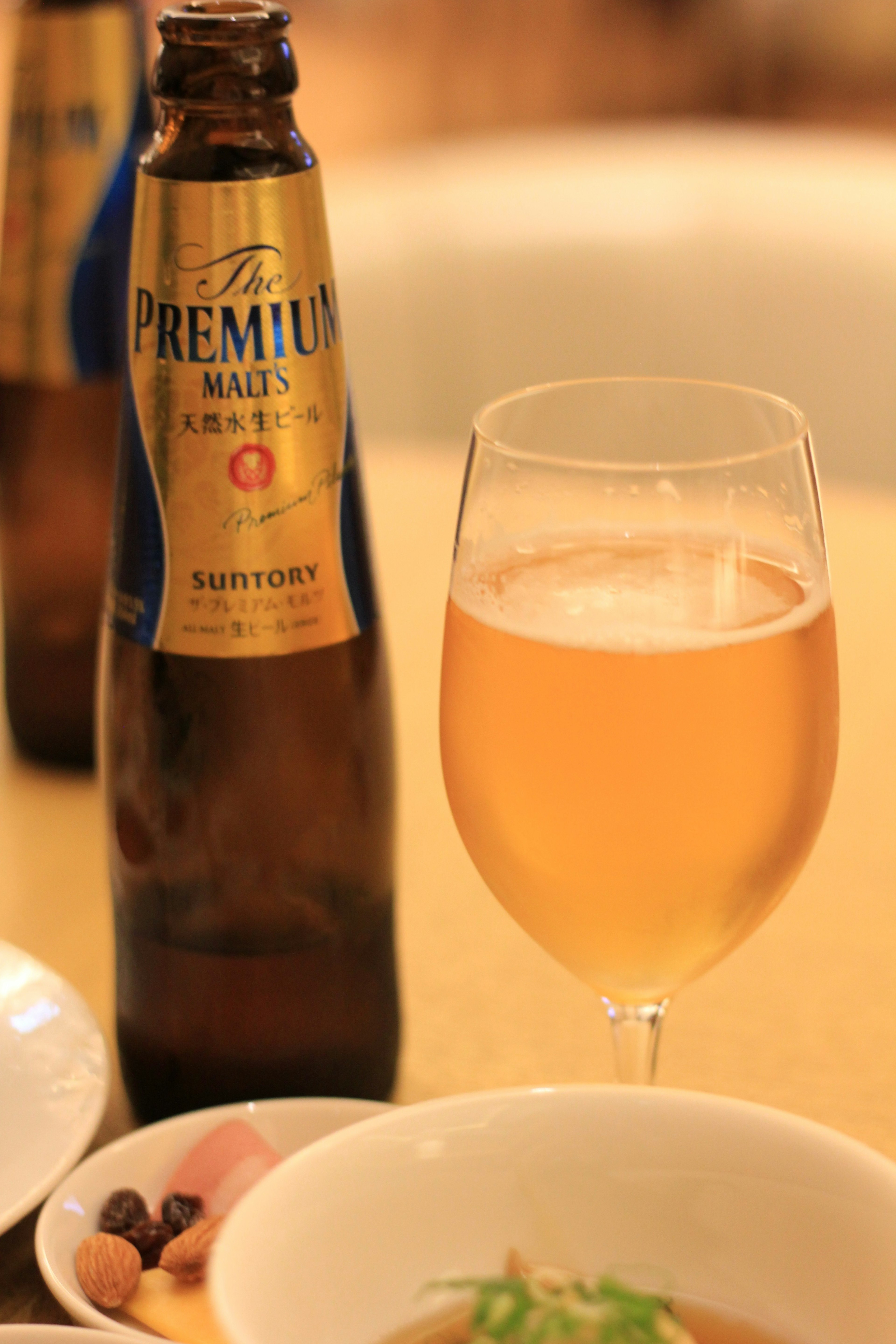 Una botella de cerveza Premium junto a un vaso de cerveza dorada en una mesa