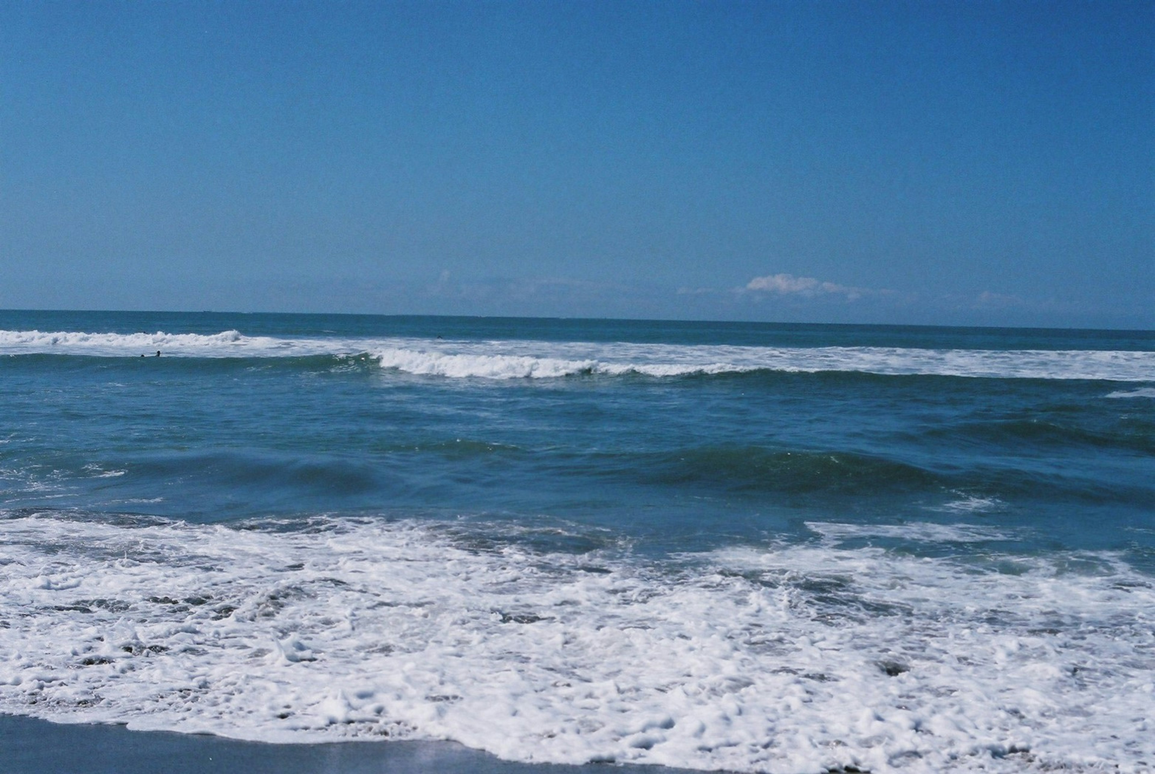 A scenic view of blue ocean waves and white foam on a beach