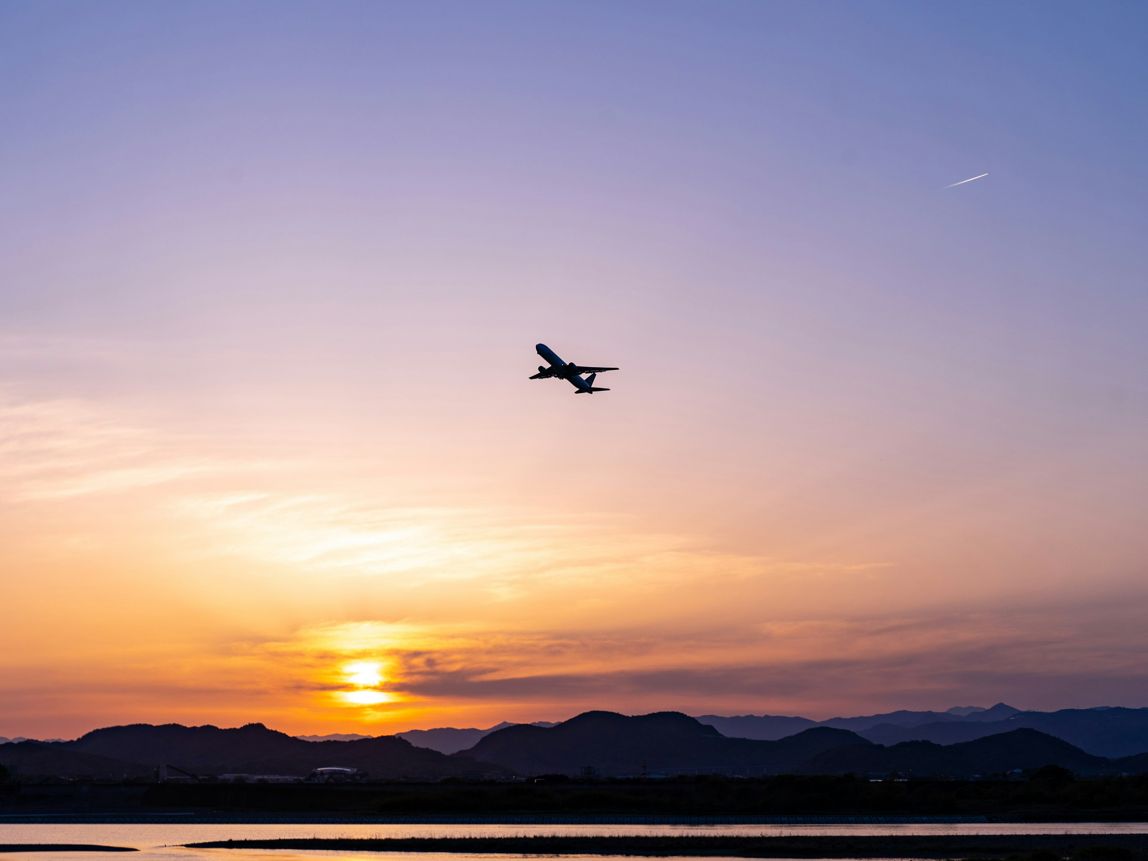 夕焼けの空を背景に飛行機が飛ぶ風景