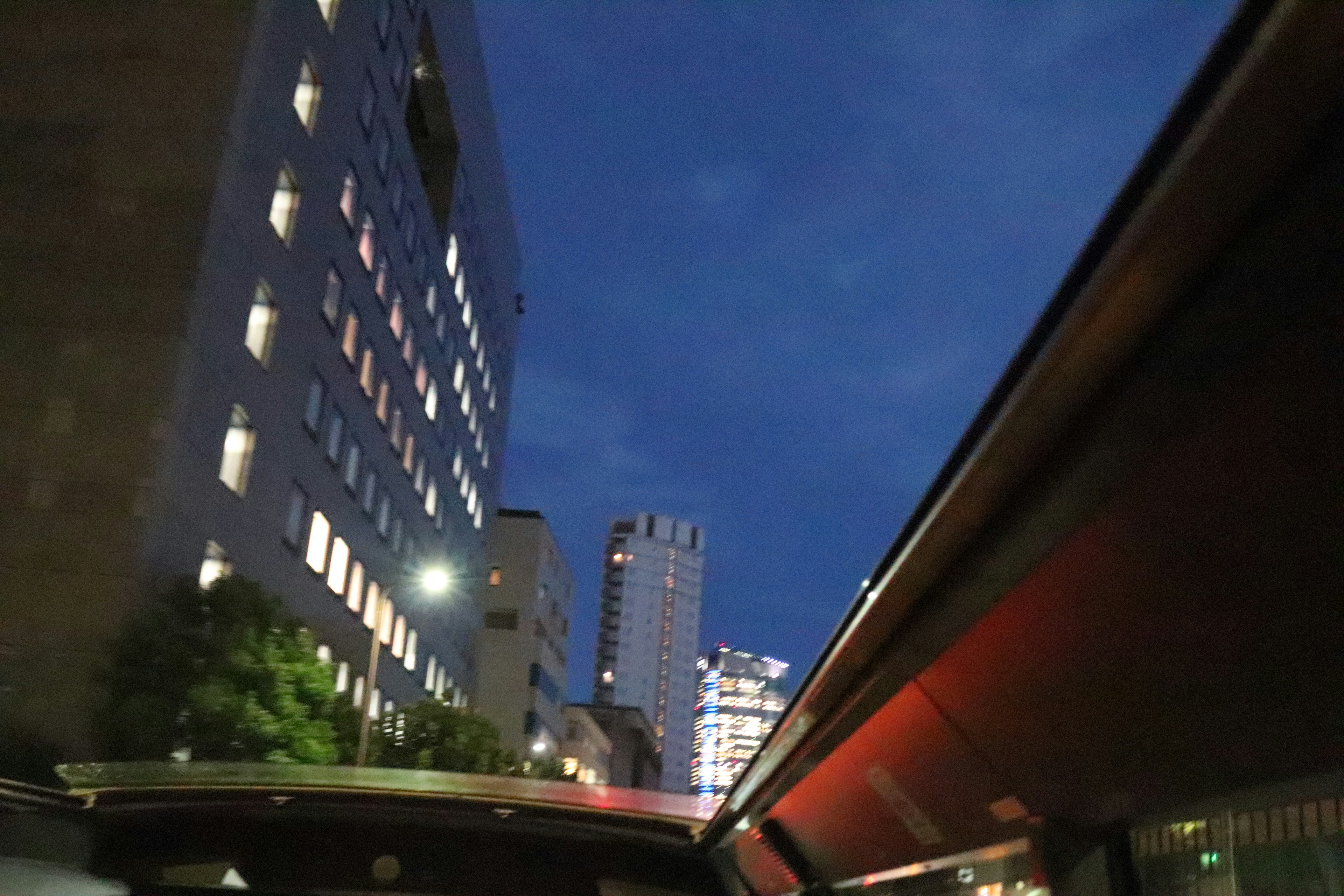 Paysage urbain nocturne avec des bâtiments illuminés vu depuis une fenêtre de voiture