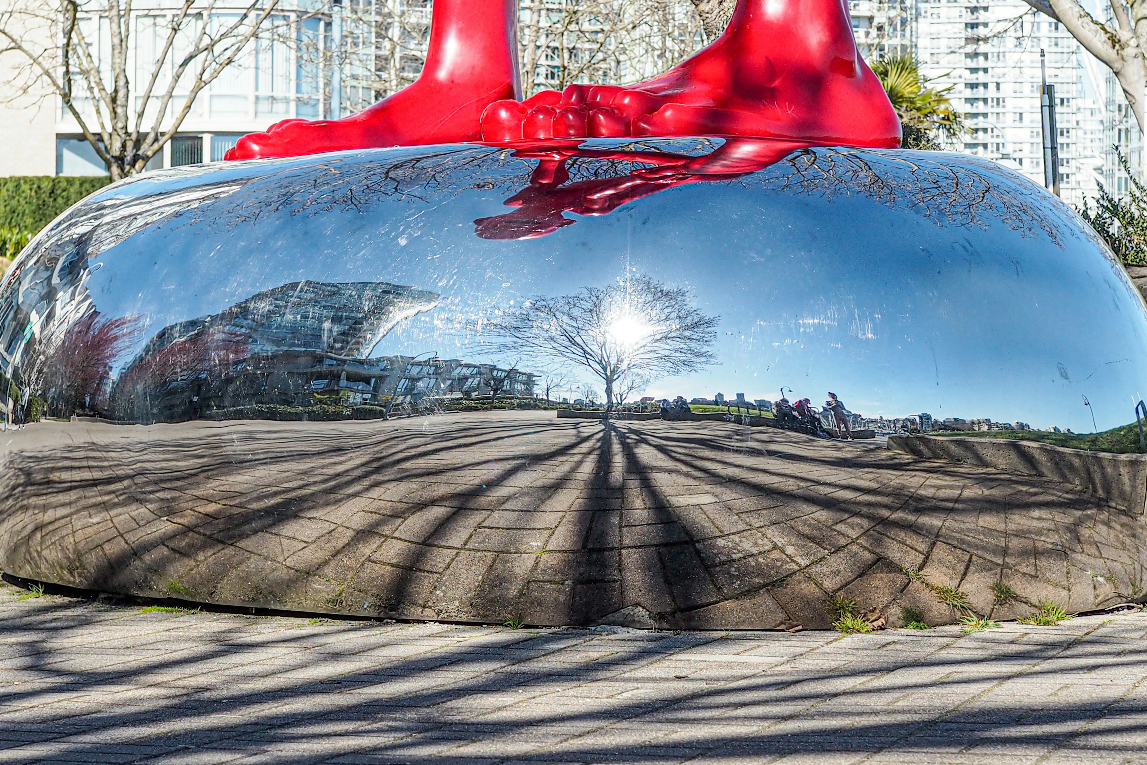 Reflexion einer Skulptur mit roten Schuhen auf einer glänzenden Oberfläche