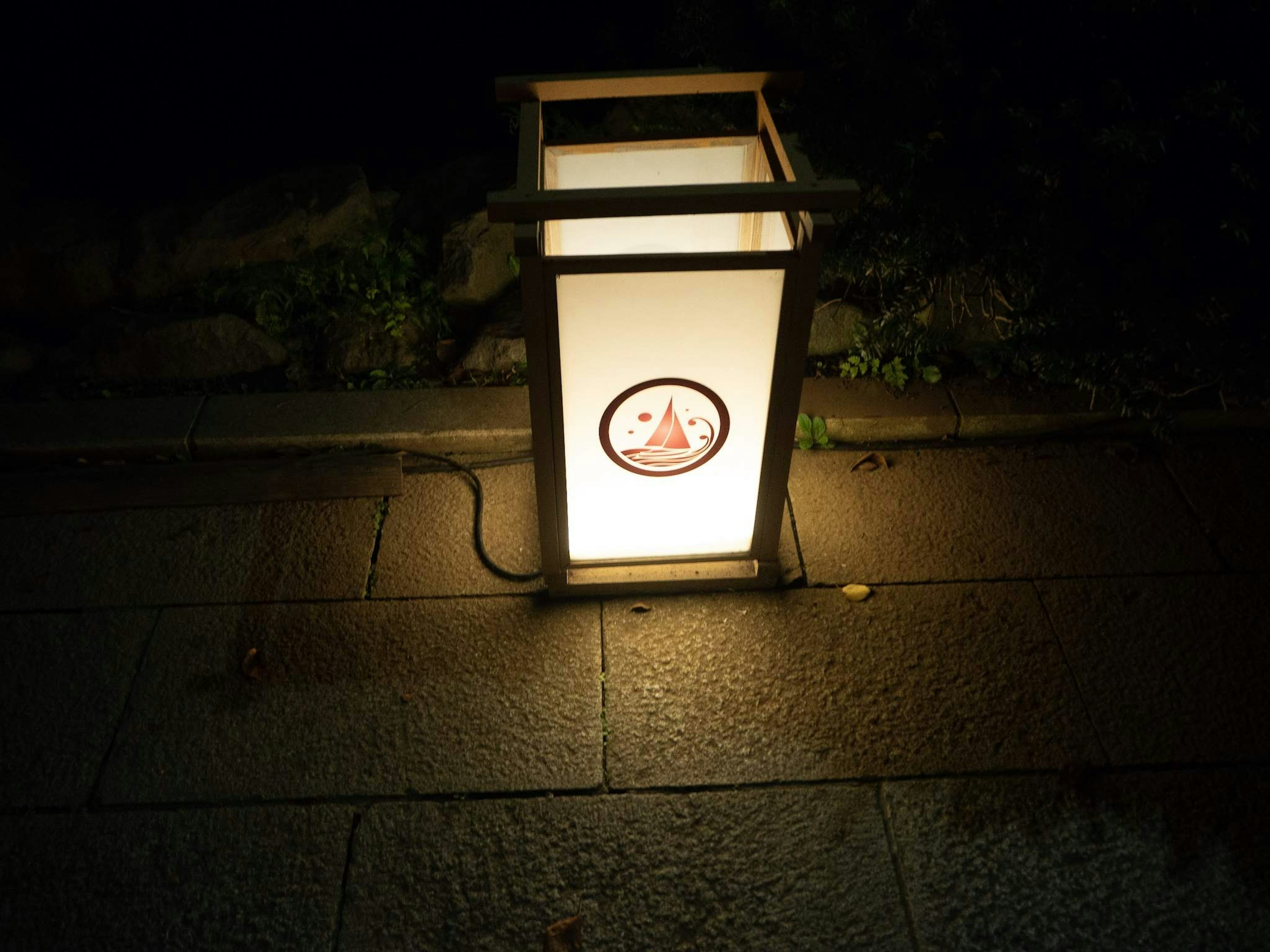 Japanese-style lantern glowing softly in the dark illuminating the surroundings