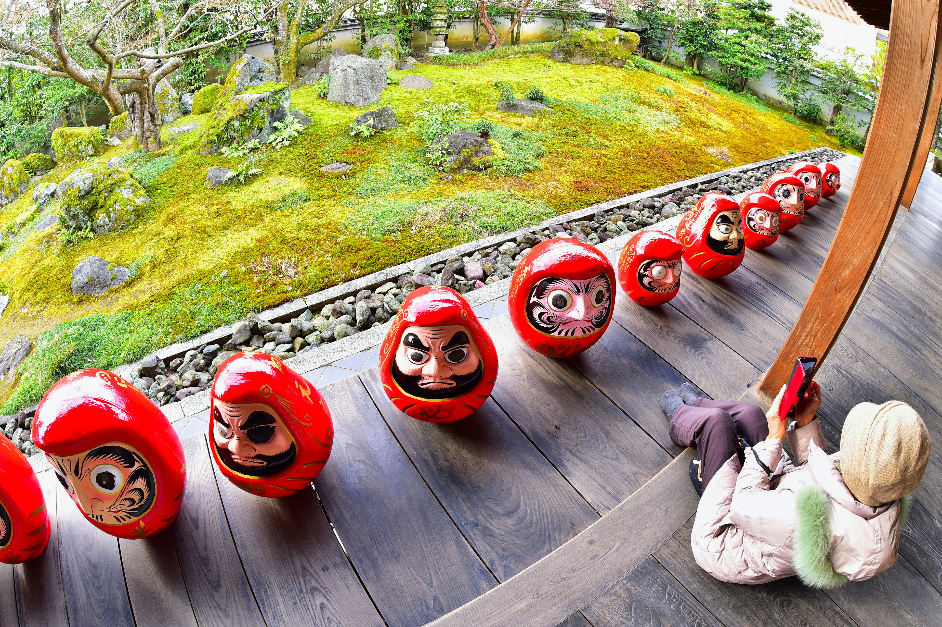 Un enfant profitant d'une vue sur des poupées Daruma rouges alignées dans un jardin