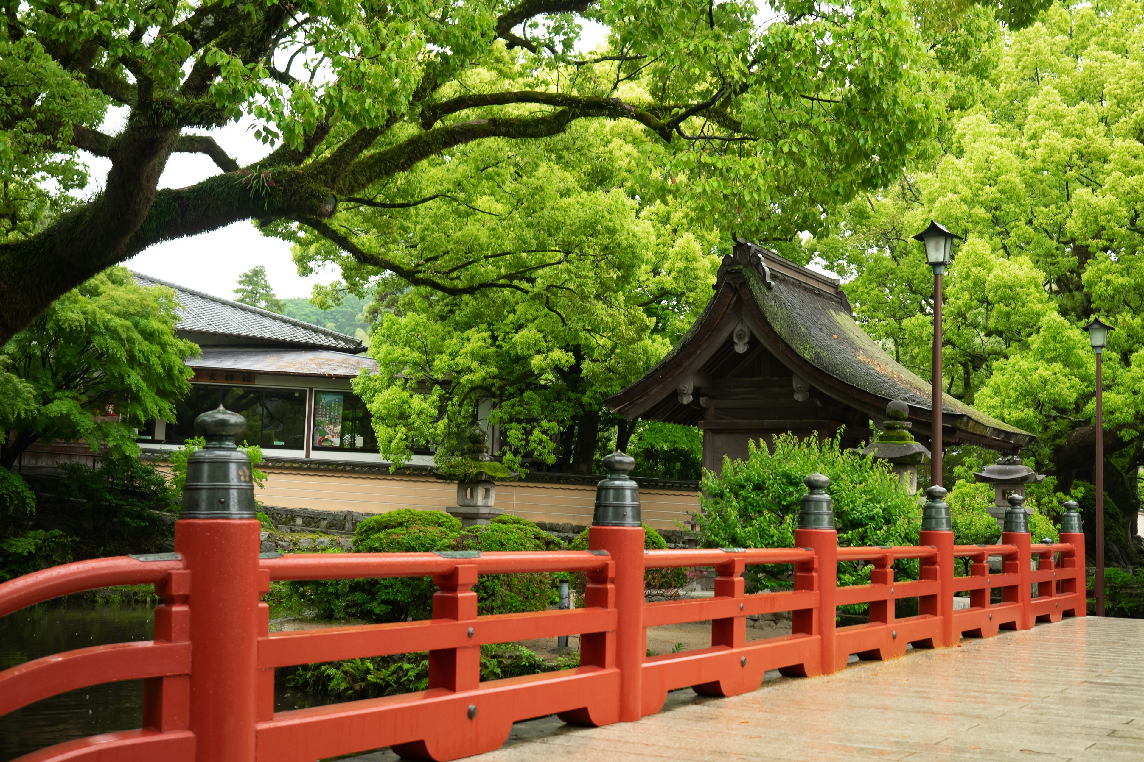 Red bridge surrounded by lush green trees and traditional Japanese architecture