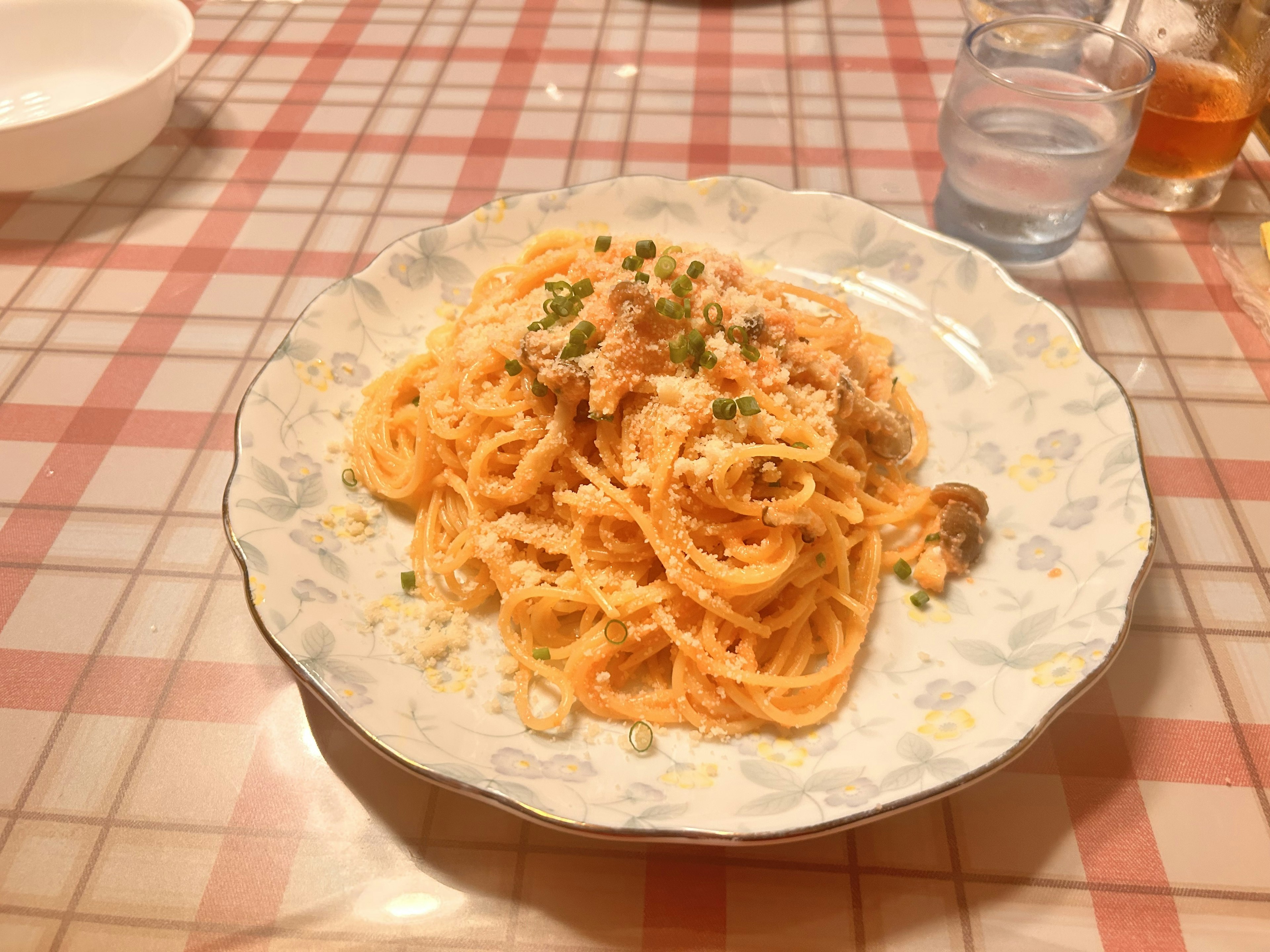 Piatto di spaghetti con salsa di panna guarnito con erbe su una tovaglia a quadretti