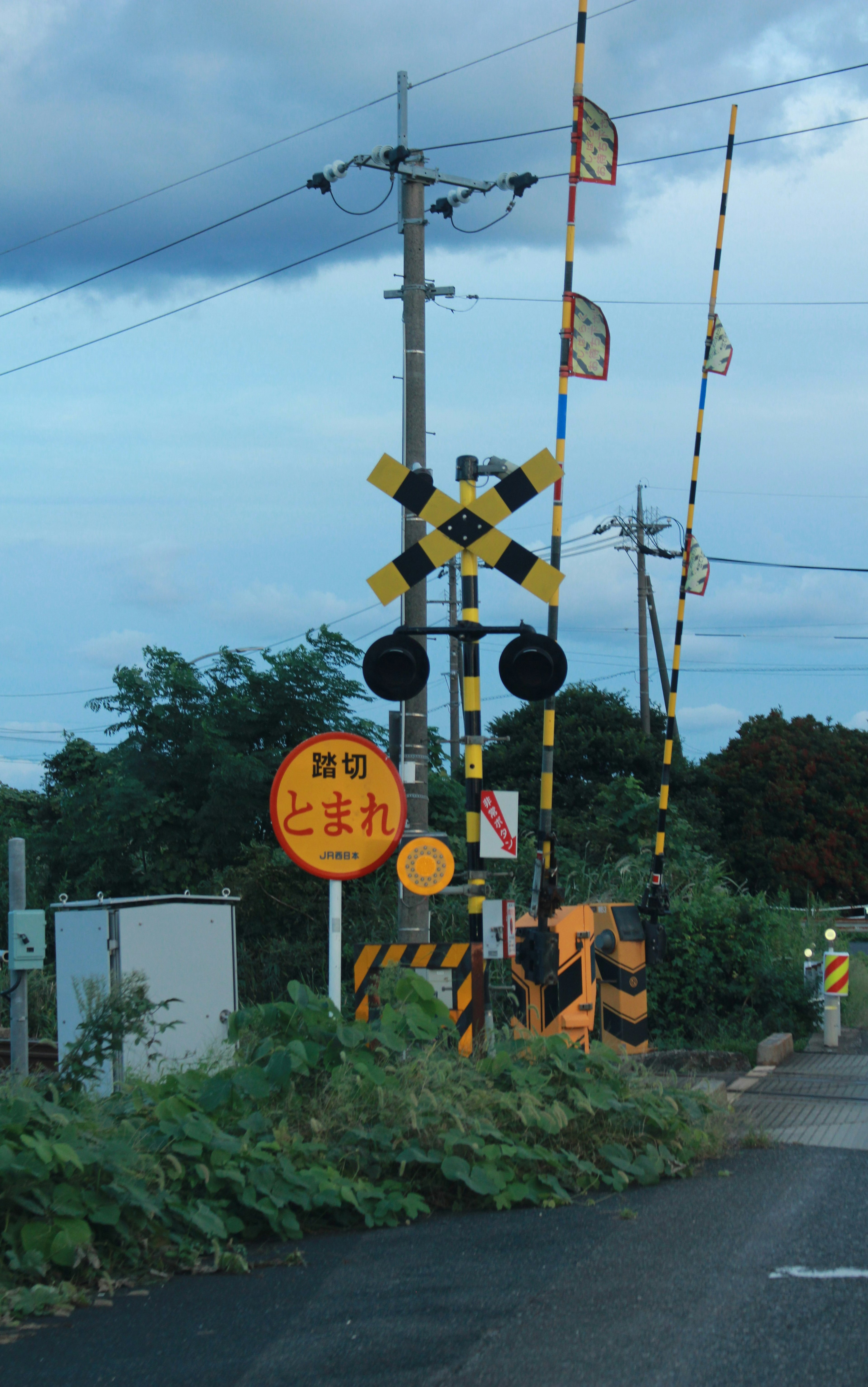 Perlintasan kereta api dengan sinyal kuning dan hitam serta penghalang