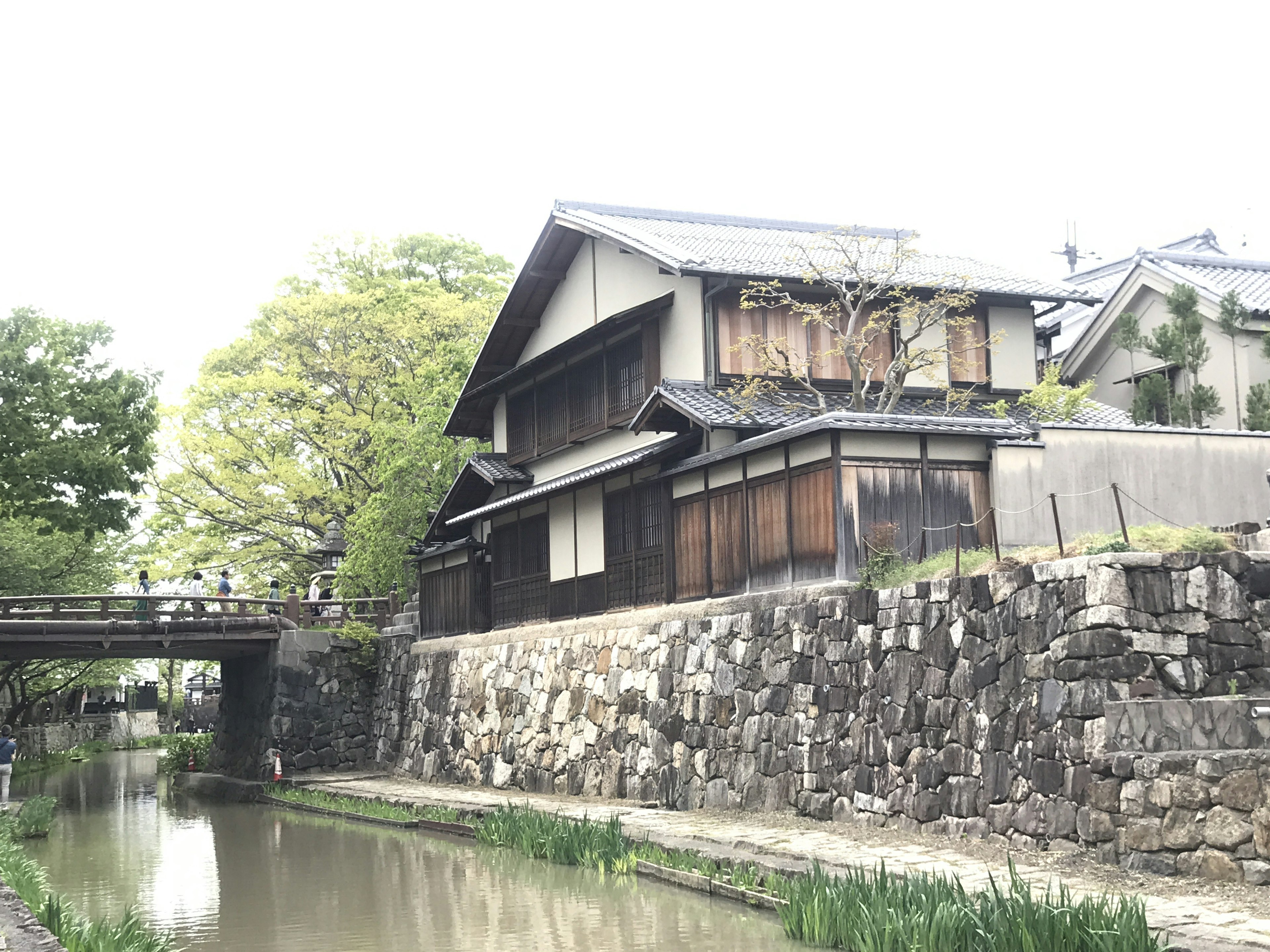 Maison japonaise traditionnelle au bord d'un cours d'eau serein avec mur en pierre