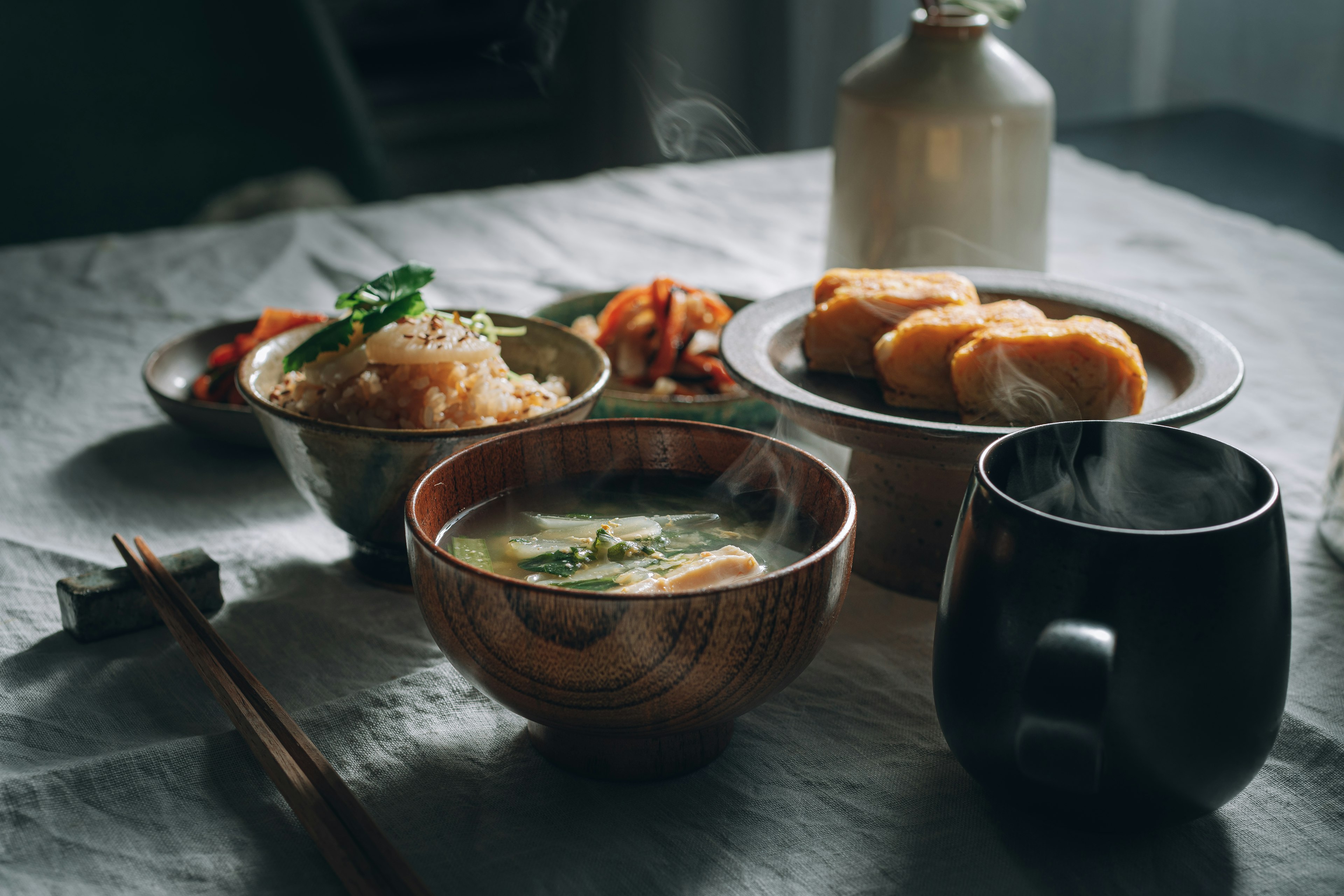 A table setting featuring a bowl of warm soup and various side dishes