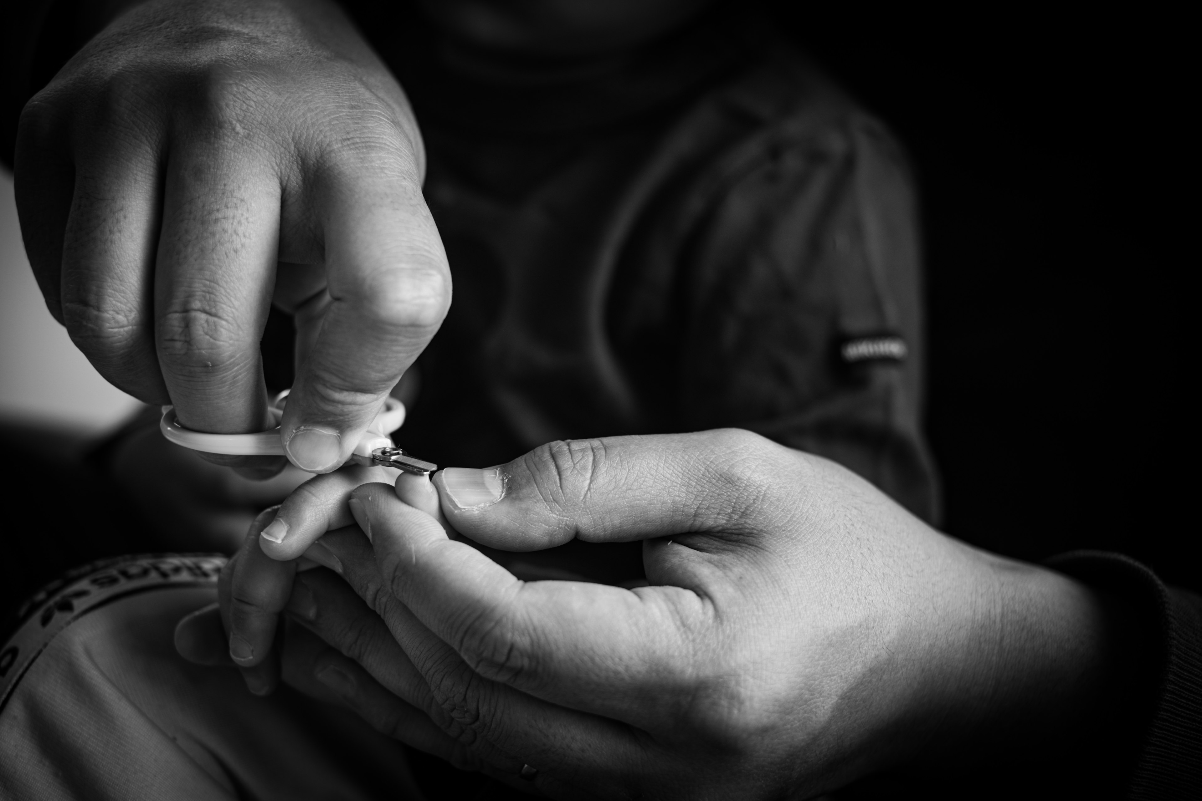 Black and white image focusing on hands trimming a child's nails