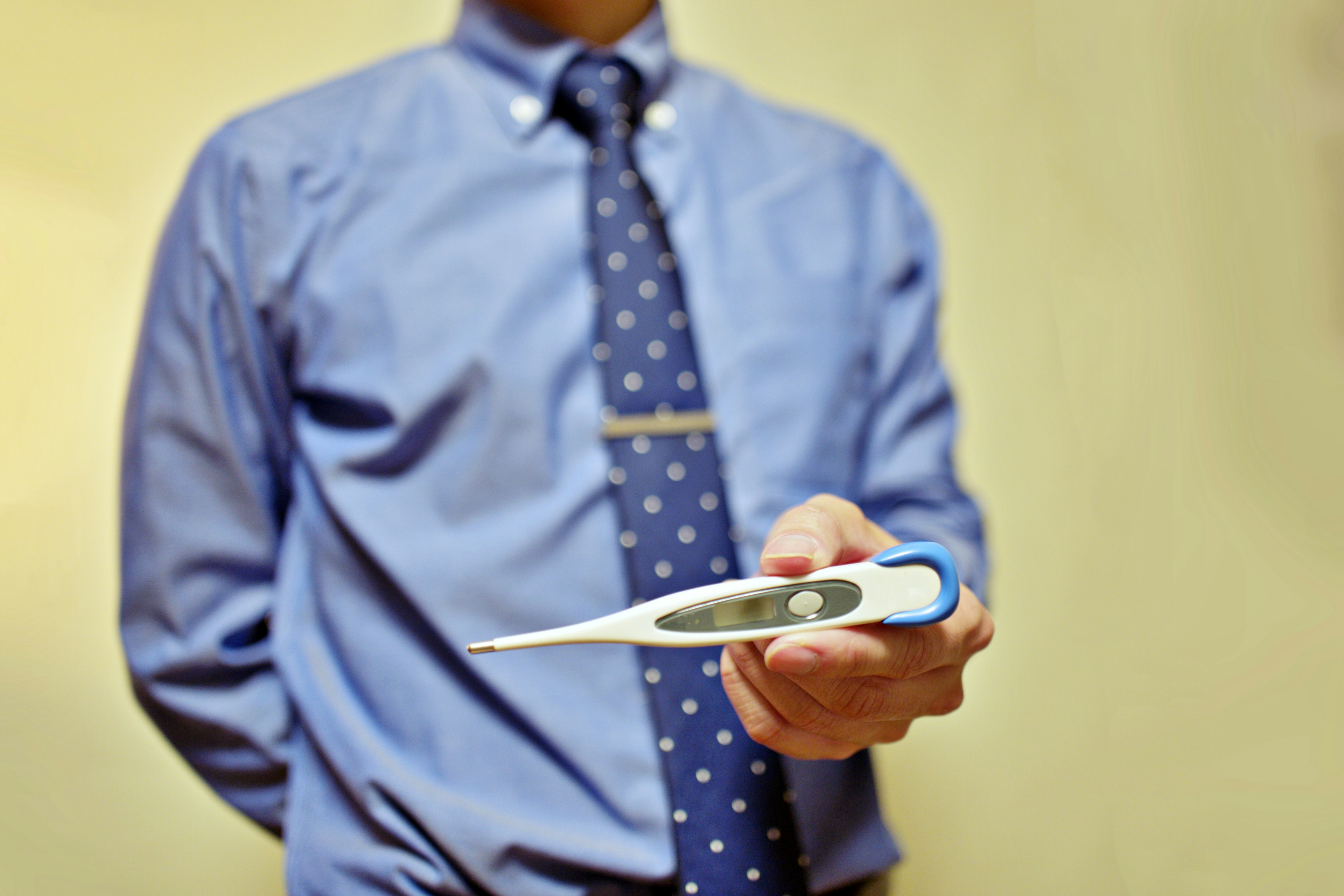 A man in a blue shirt holding a thermometer