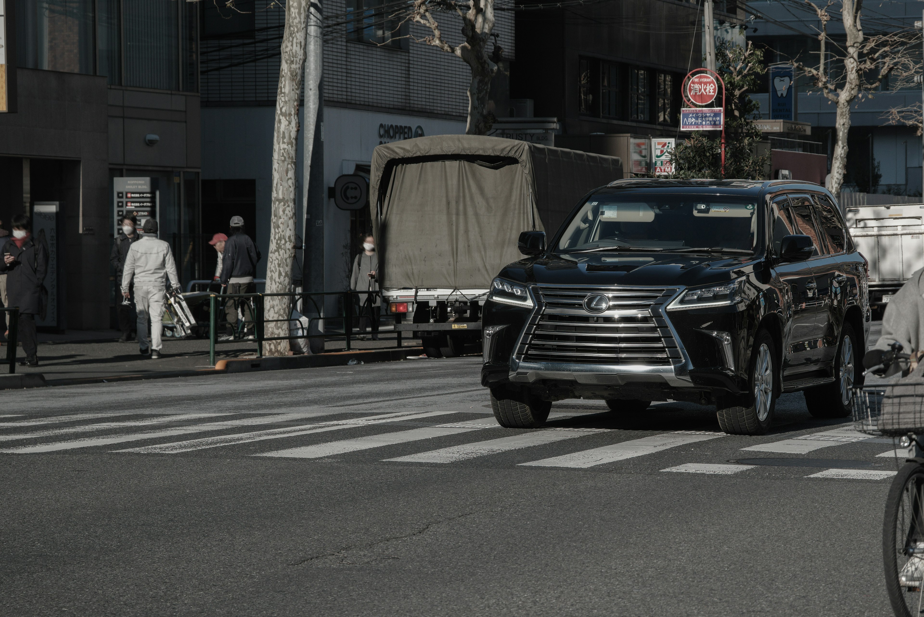 Schwarzer SUV, der auf einem Zebrastreifen in einer städtischen Umgebung fährt