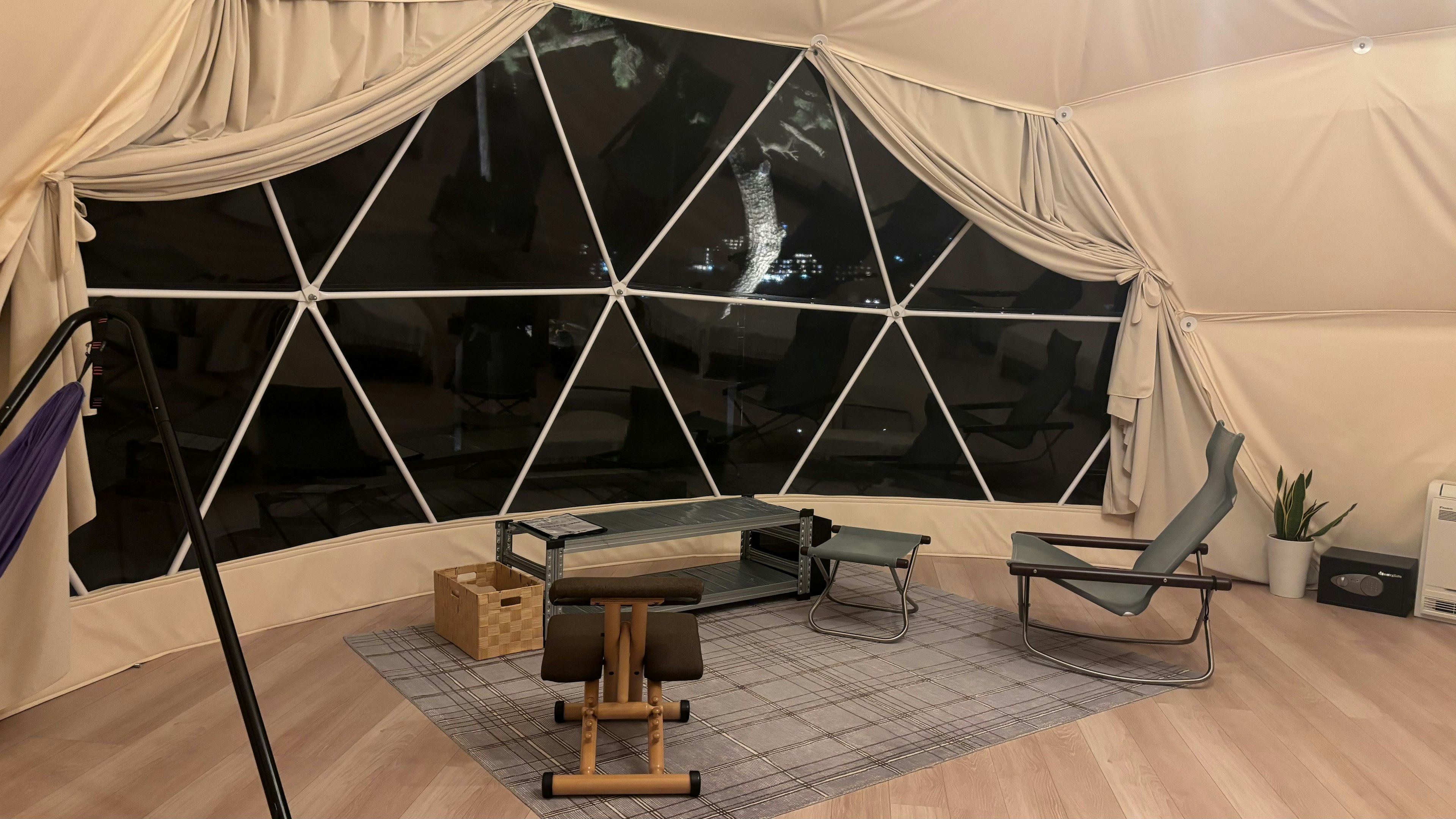 Interior of a geodesic dome featuring simple furniture and large windows