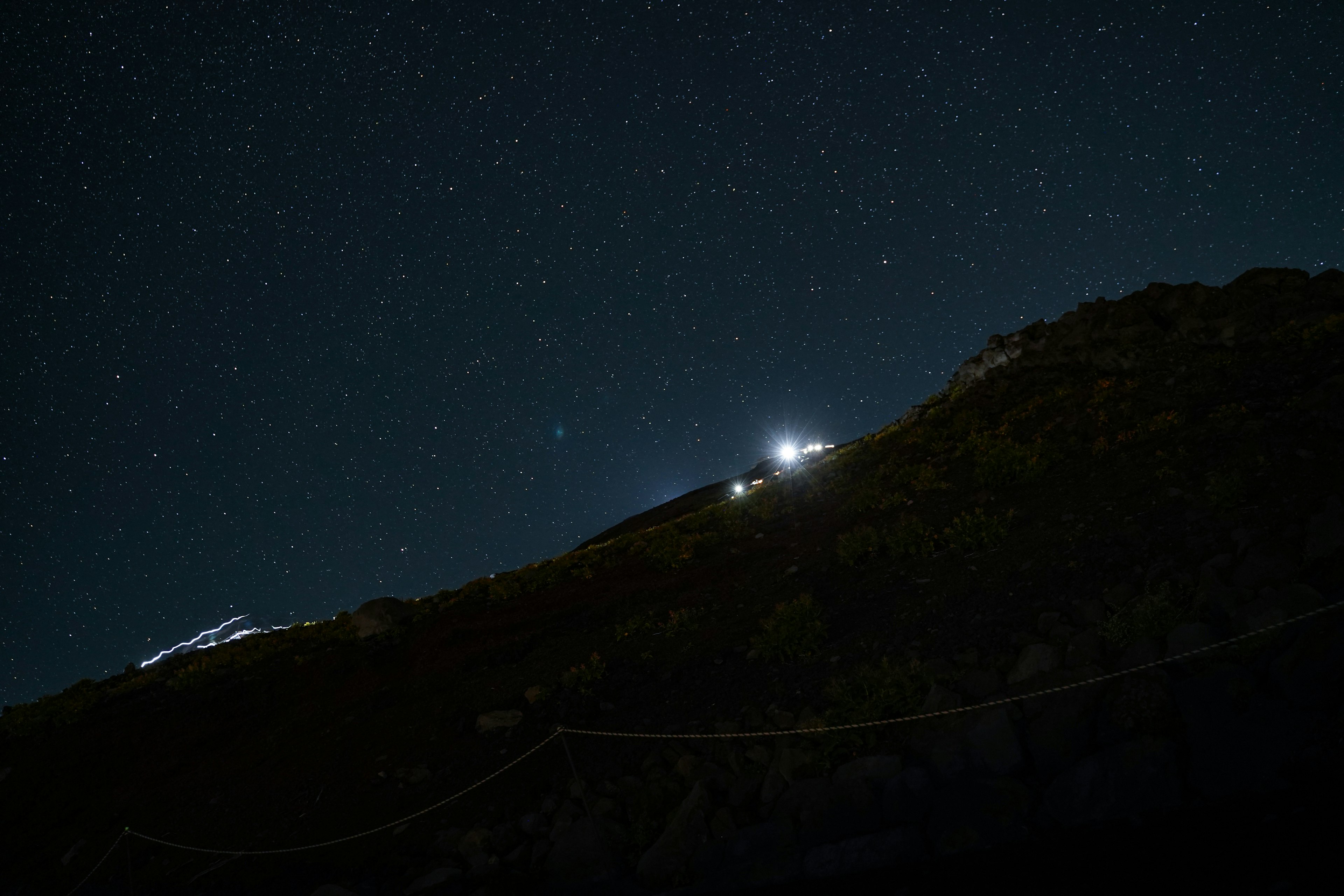 Langit malam dipenuhi bintang dan siluet gunung