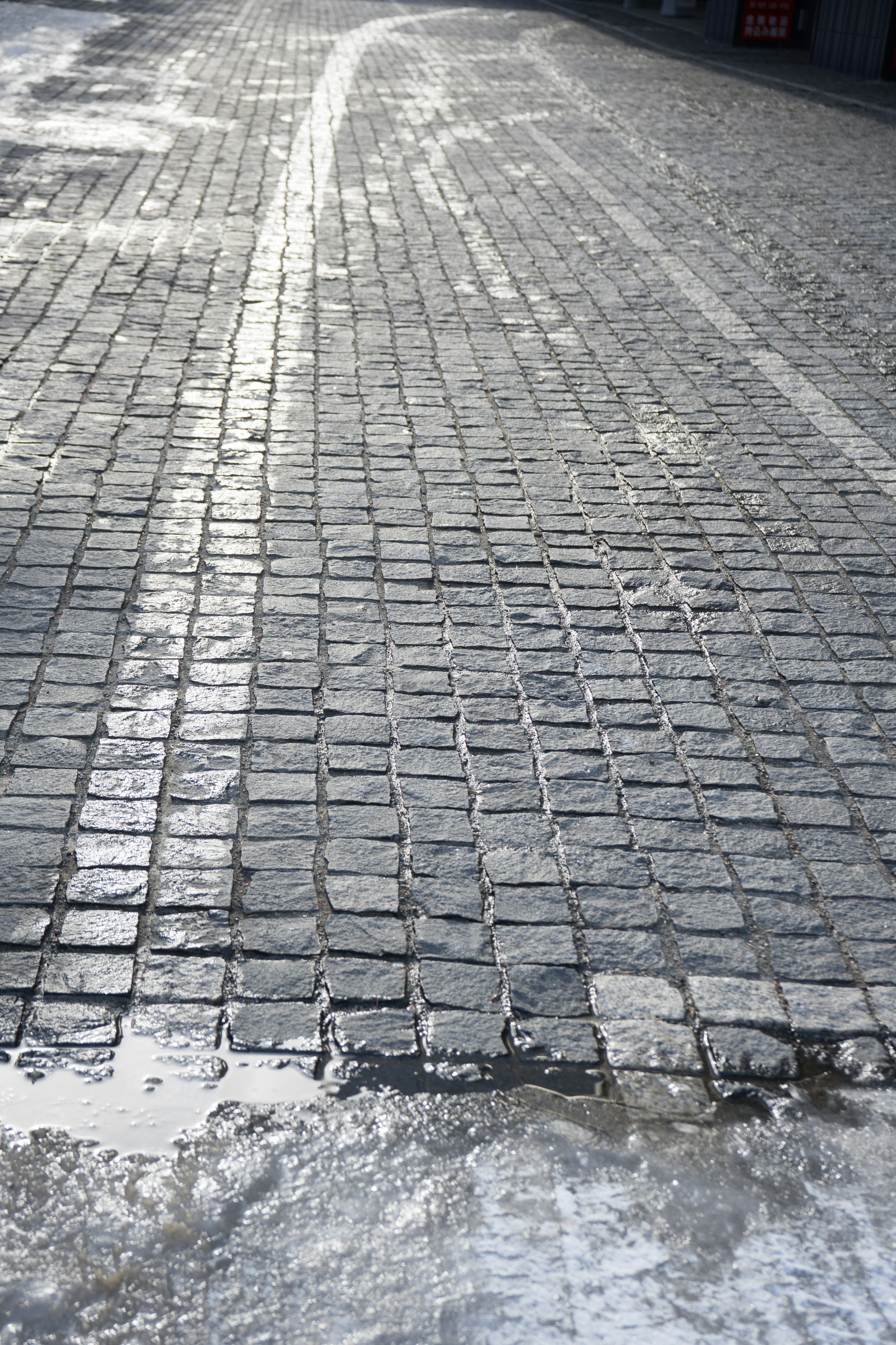 Rue en pavés mouillés avec des traces de pneus visibles