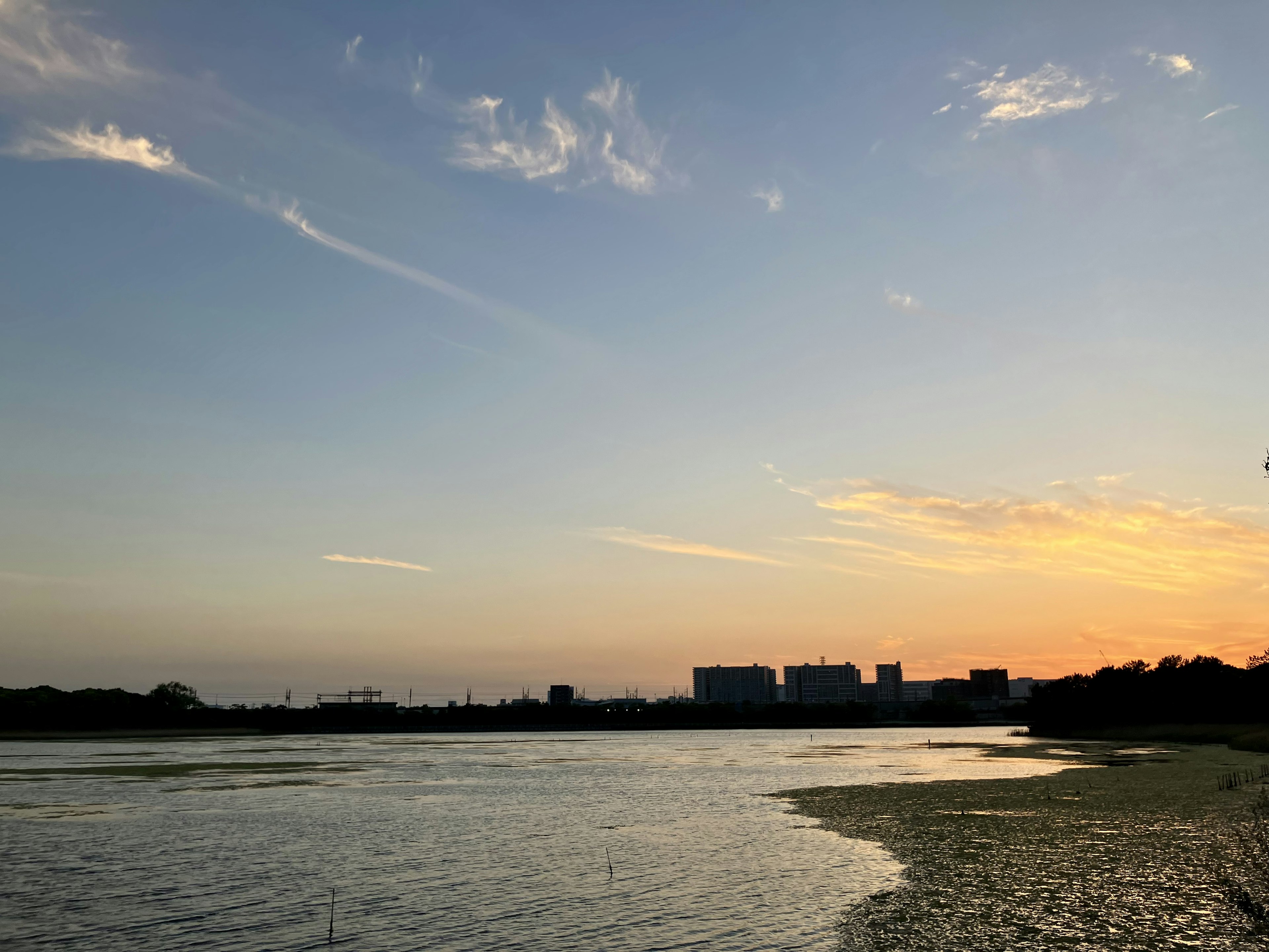 Hermoso paisaje con cielo al atardecer y superficie de agua que presenta un río y edificios