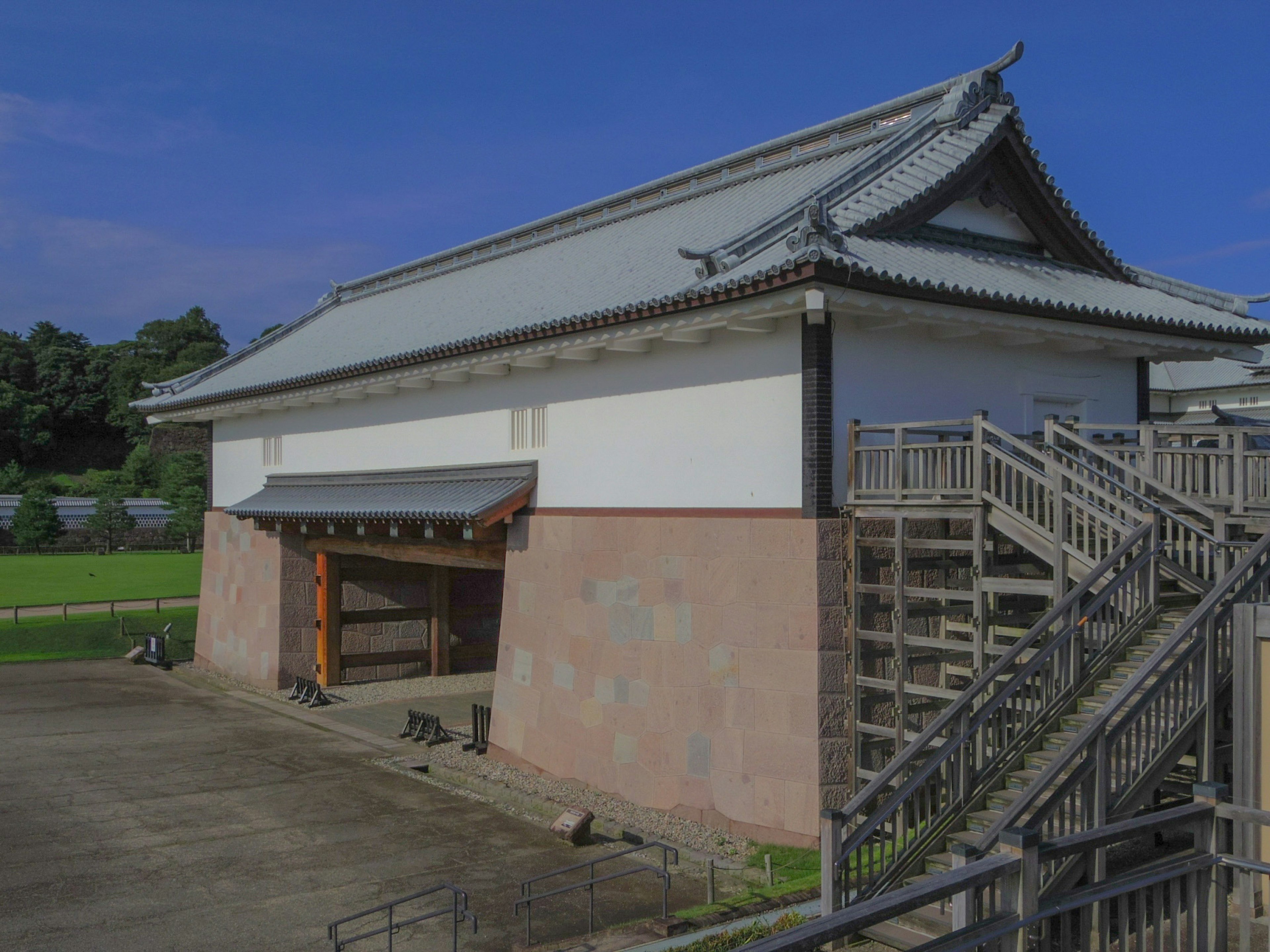 Extérieur d'un bâtiment japonais traditionnel avec des murs blancs et un toit distinctif comportant des escaliers en bois