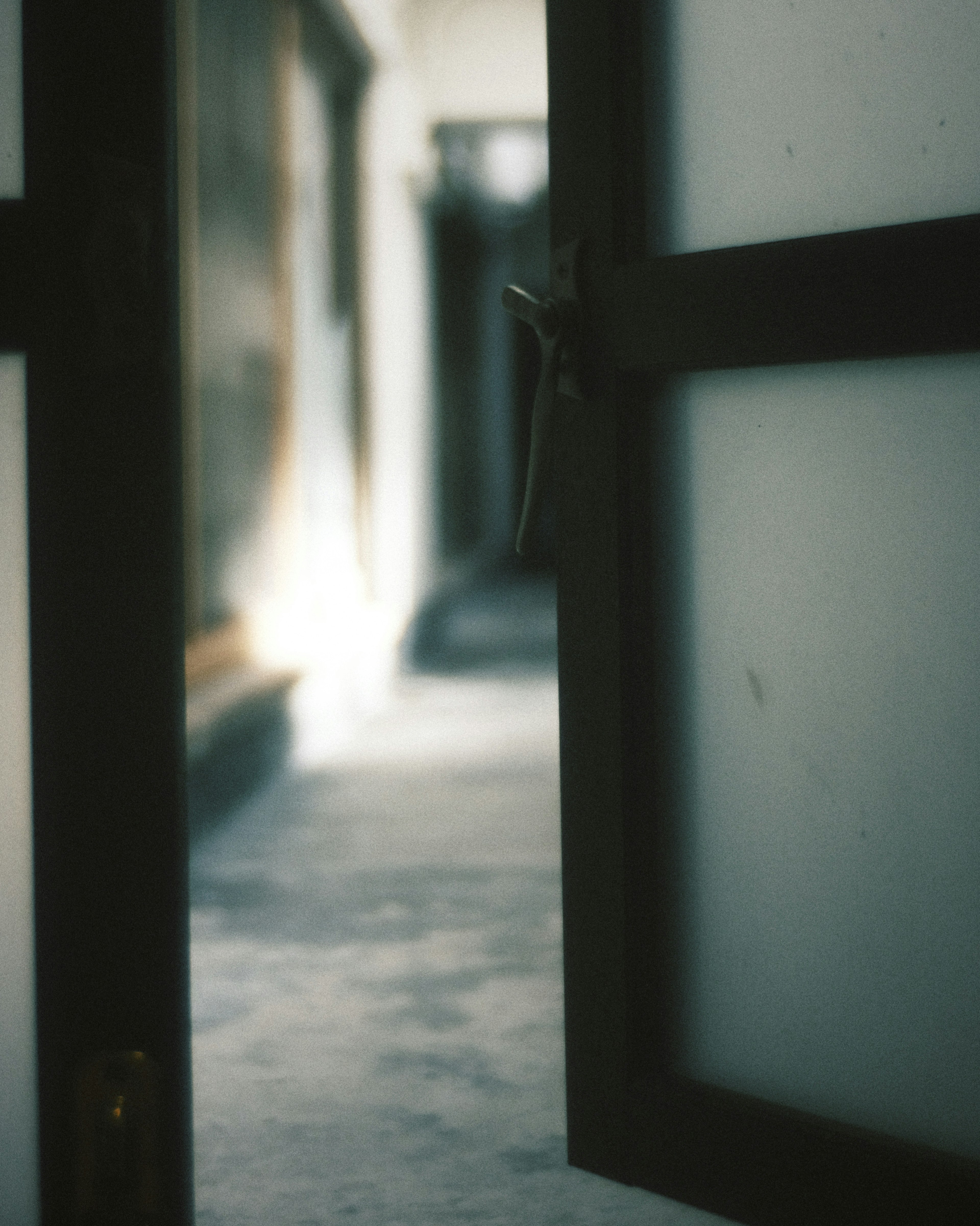 Open glass door revealing a blurred hallway beyond