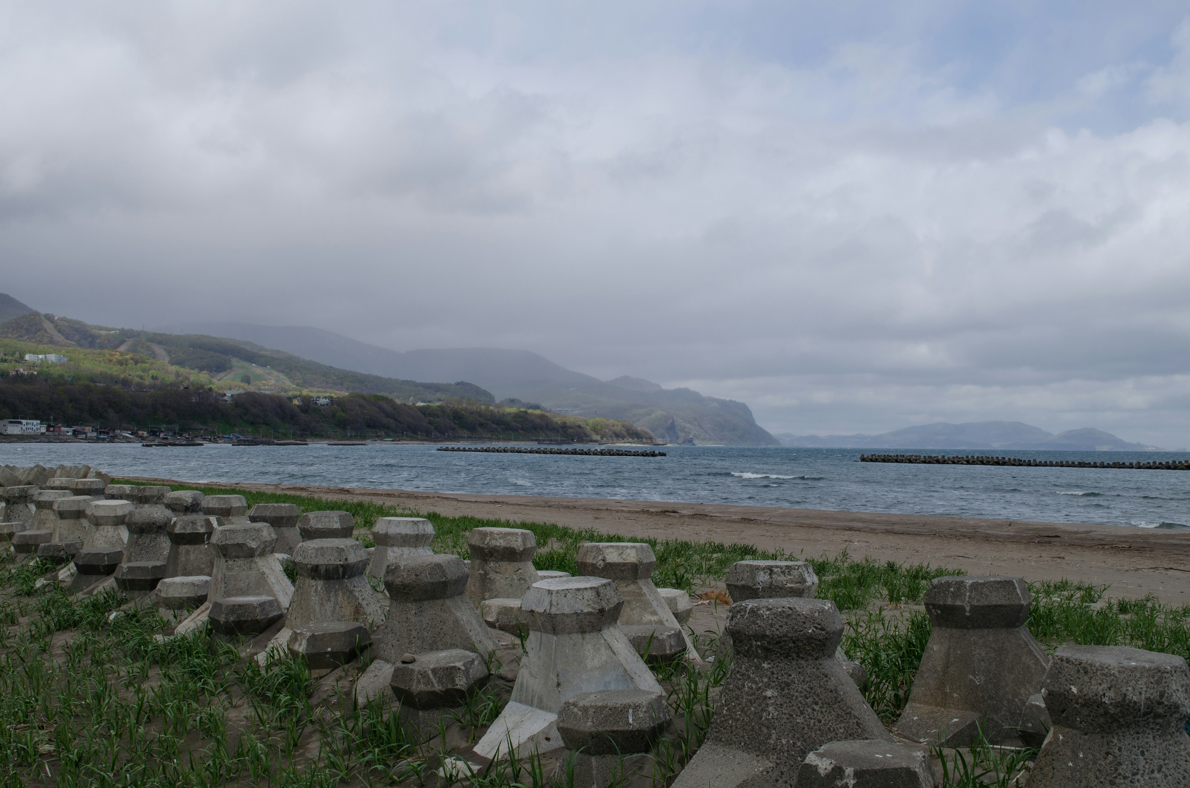 Blocs en béton le long d'une plage avec une mer calme et un ciel nuageux