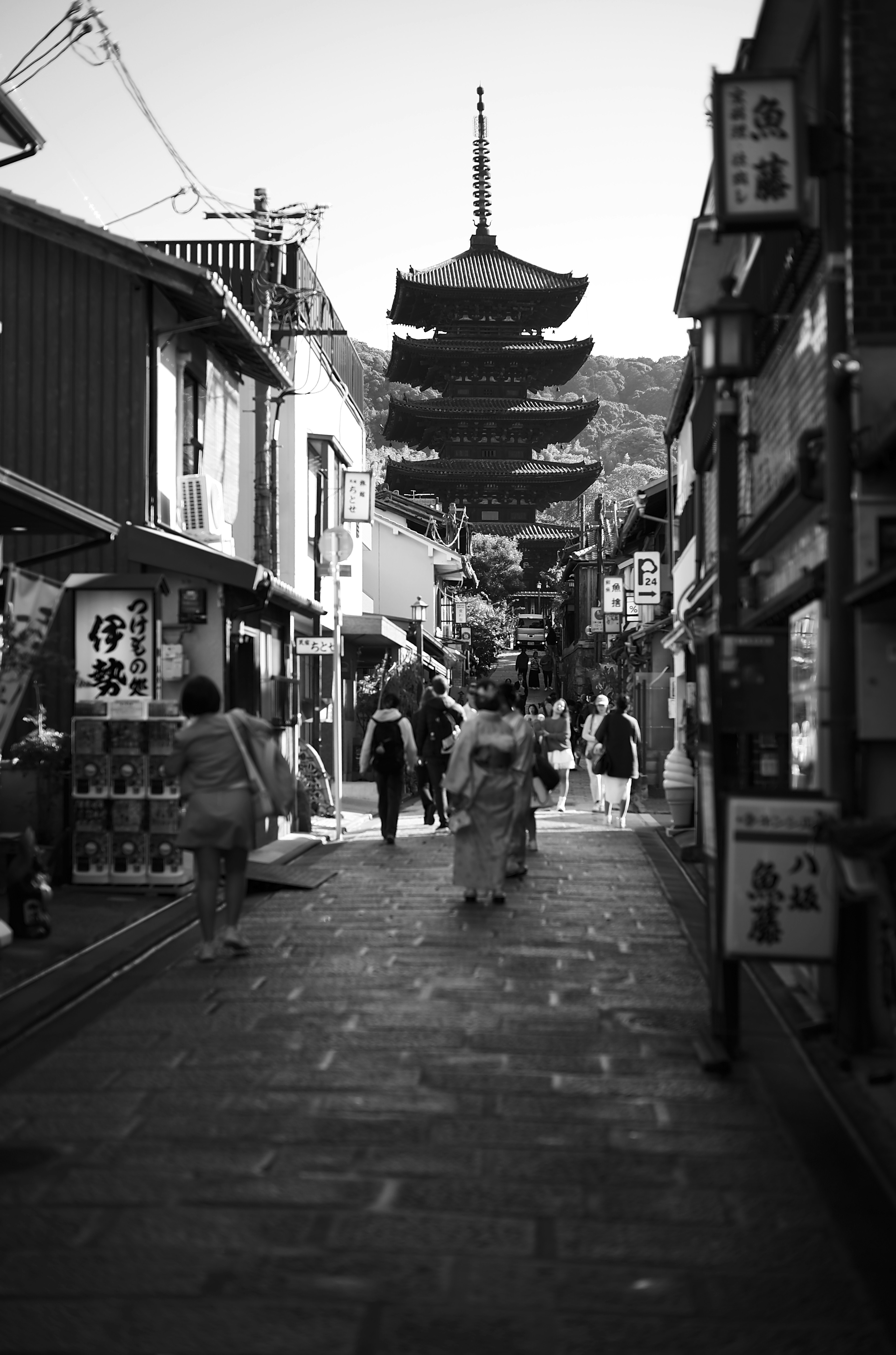 People walking in an old street with a five-story pagoda in the background