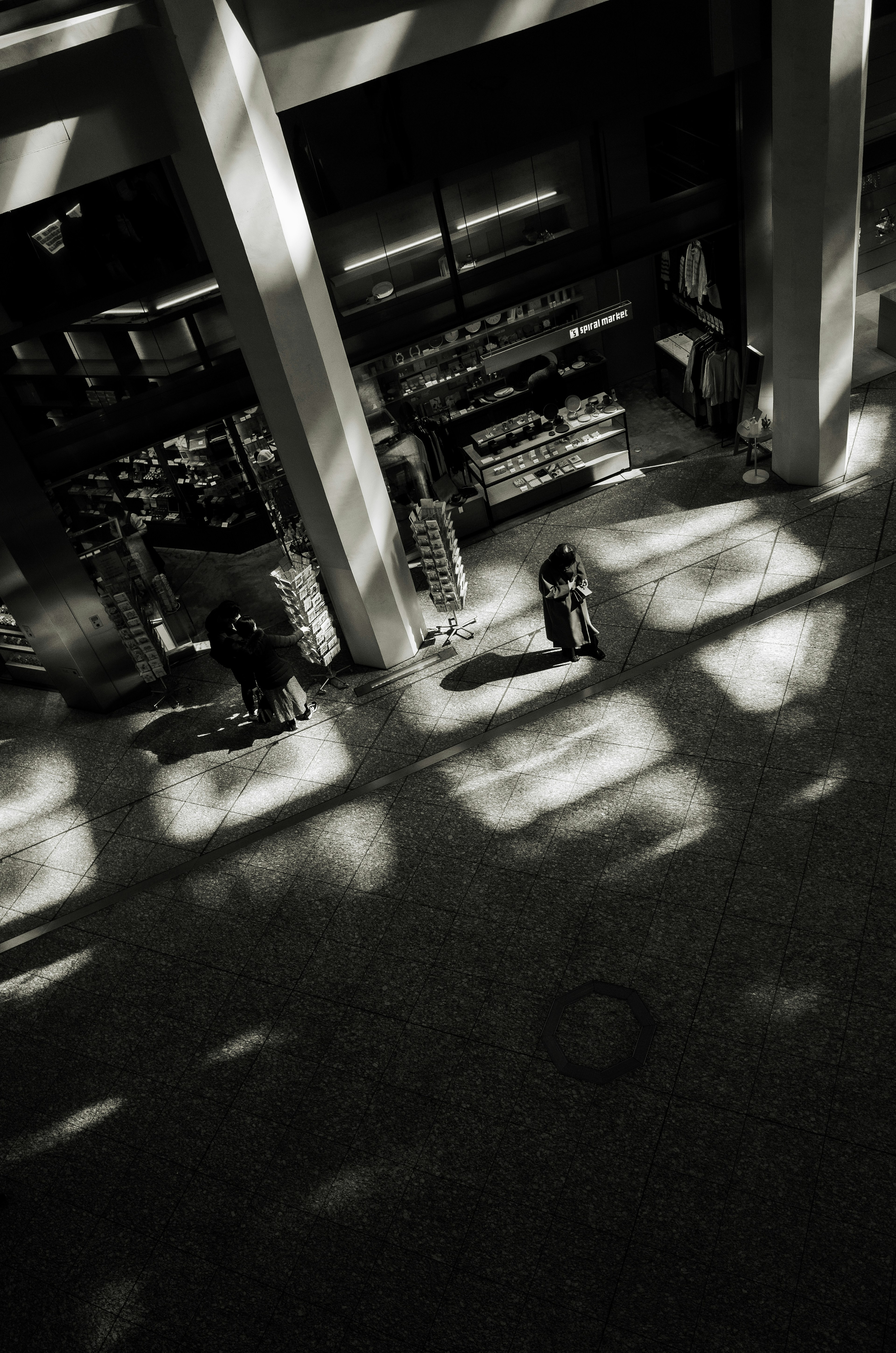 Vista interior de un edificio con luz y sombras entrelazadas con personas