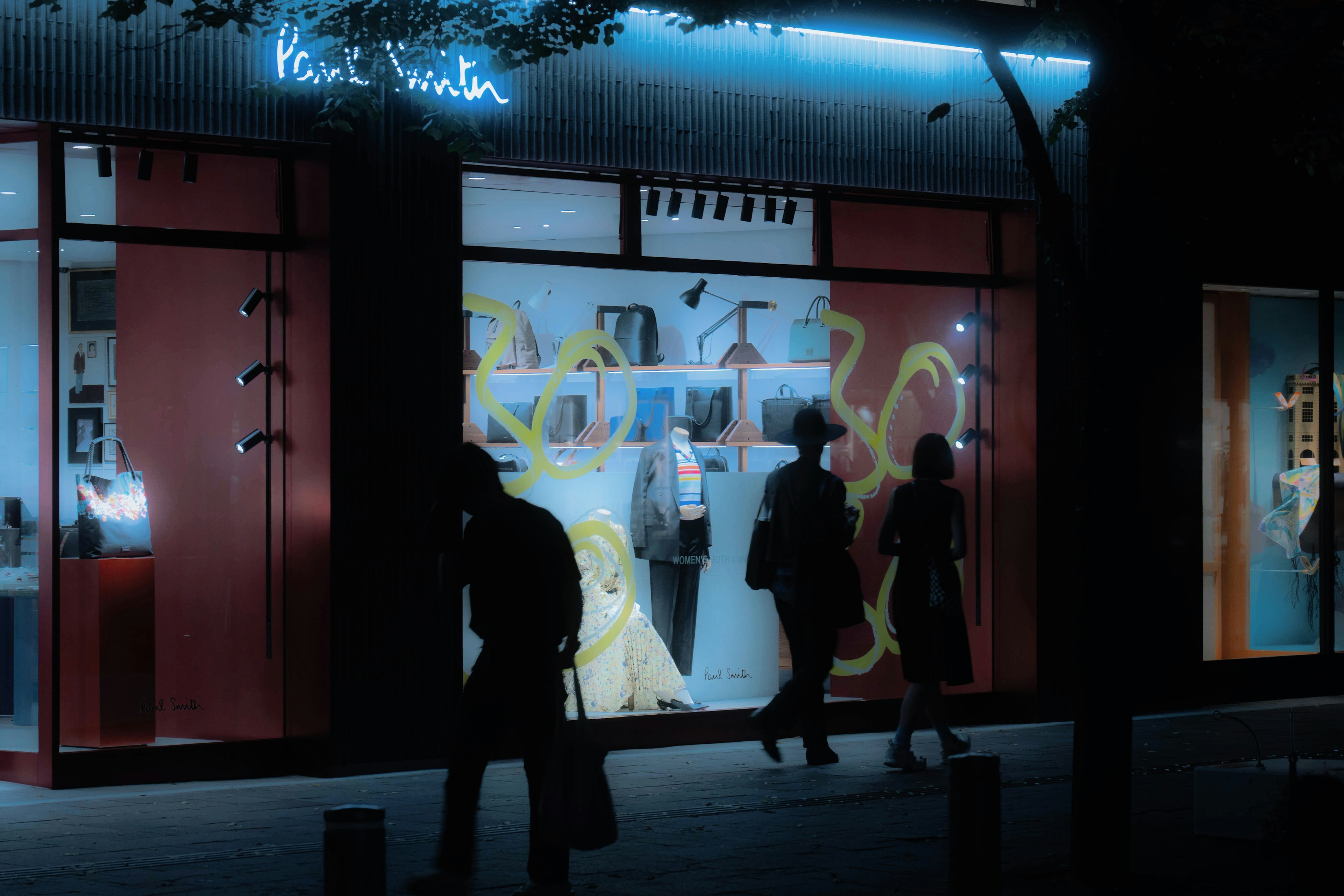 Magasin Paul Smith illuminé la nuit avec des piétons