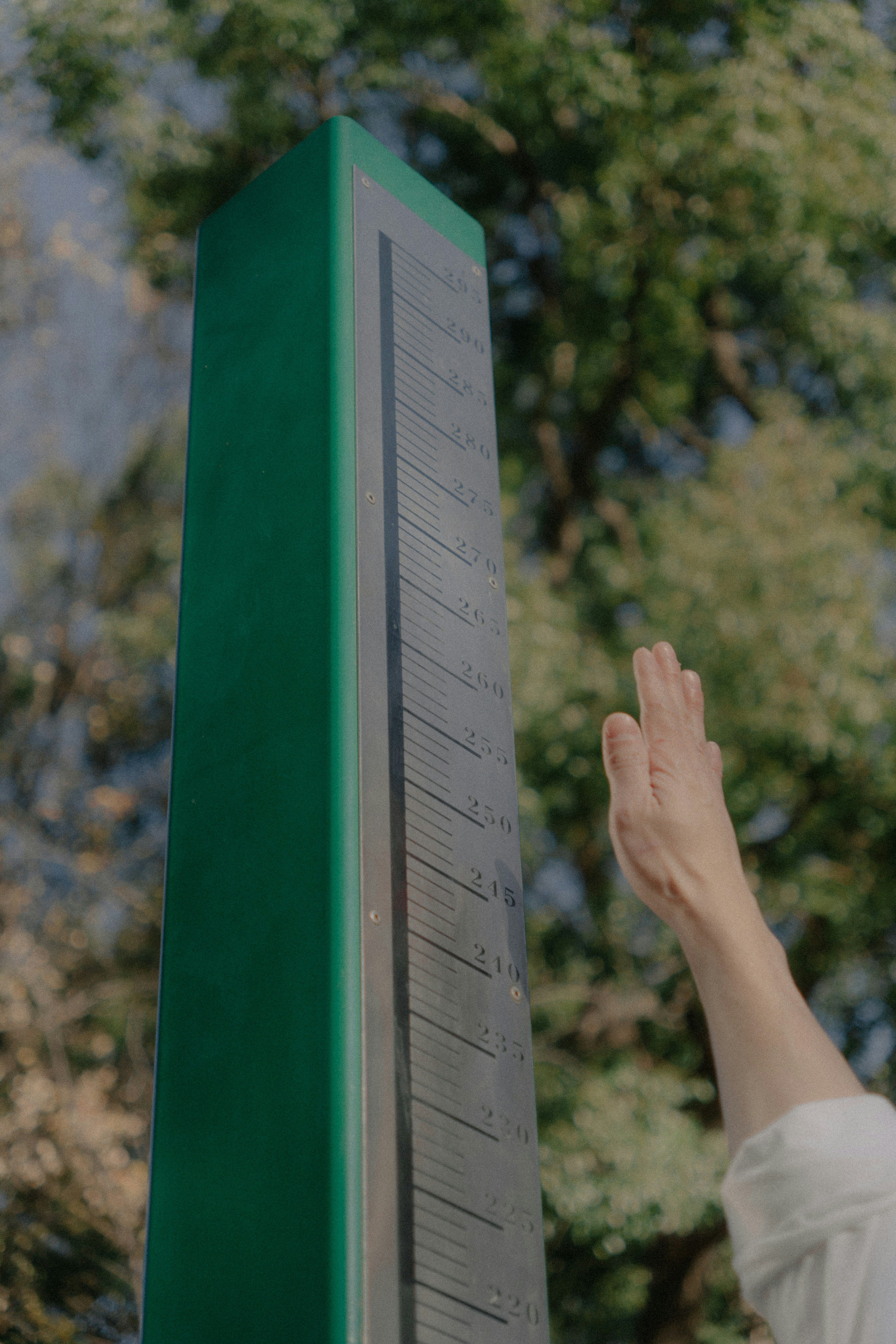 Person raising hand near a green pillar with solar panels