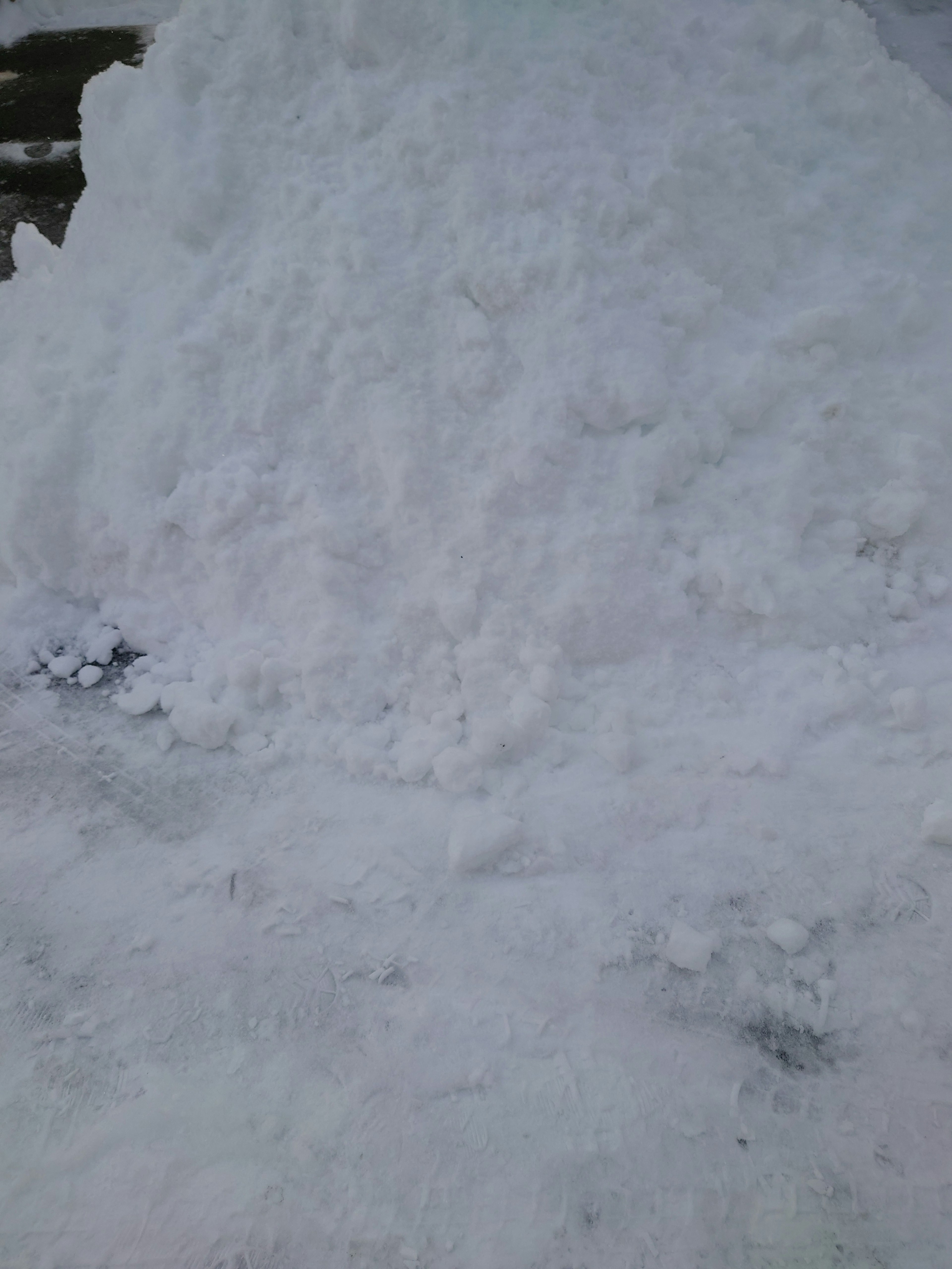 Un grand tas de neige avec un sol enneigé