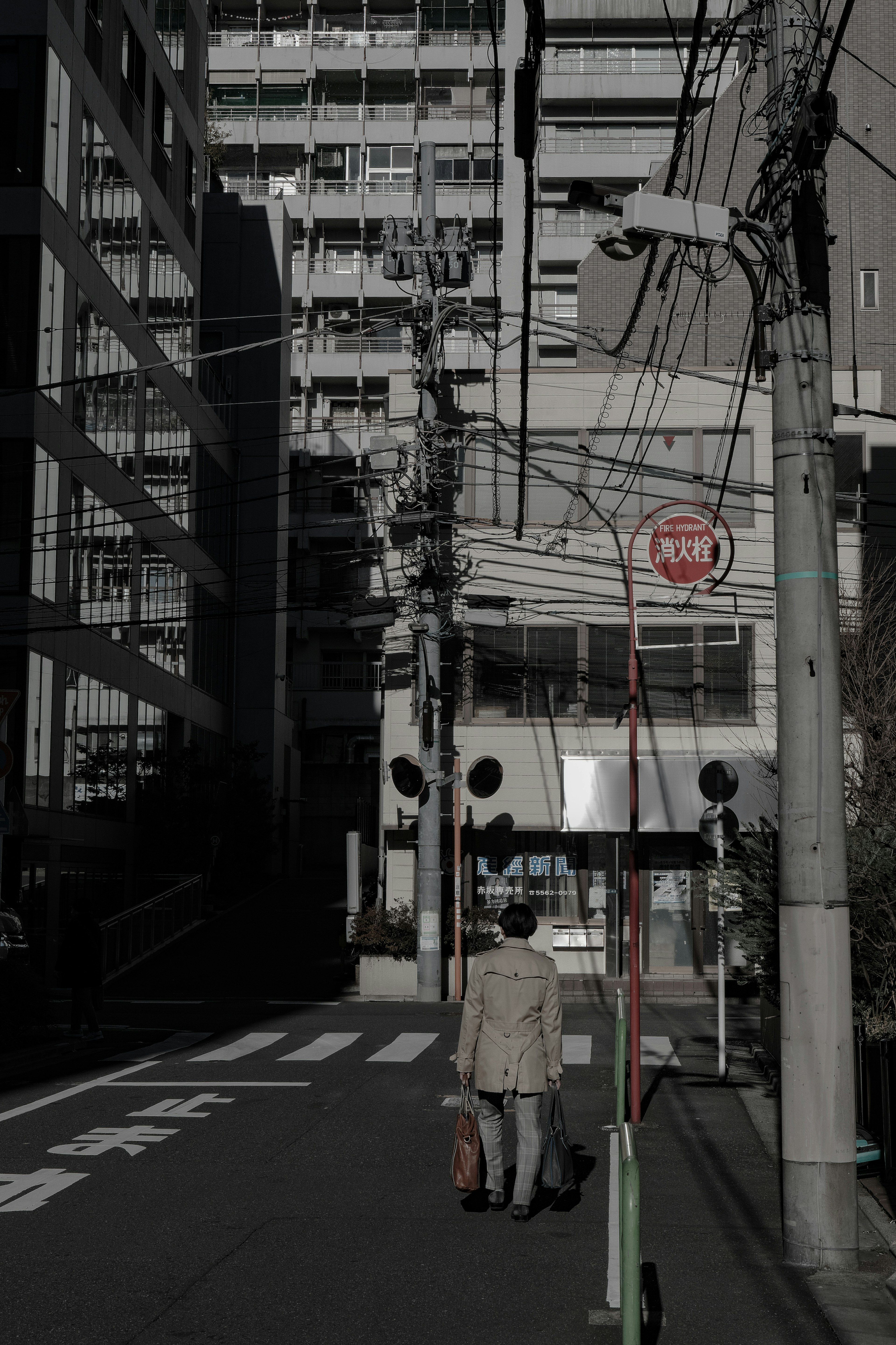 暗い街並みを歩く人物と高層ビルが映る画像