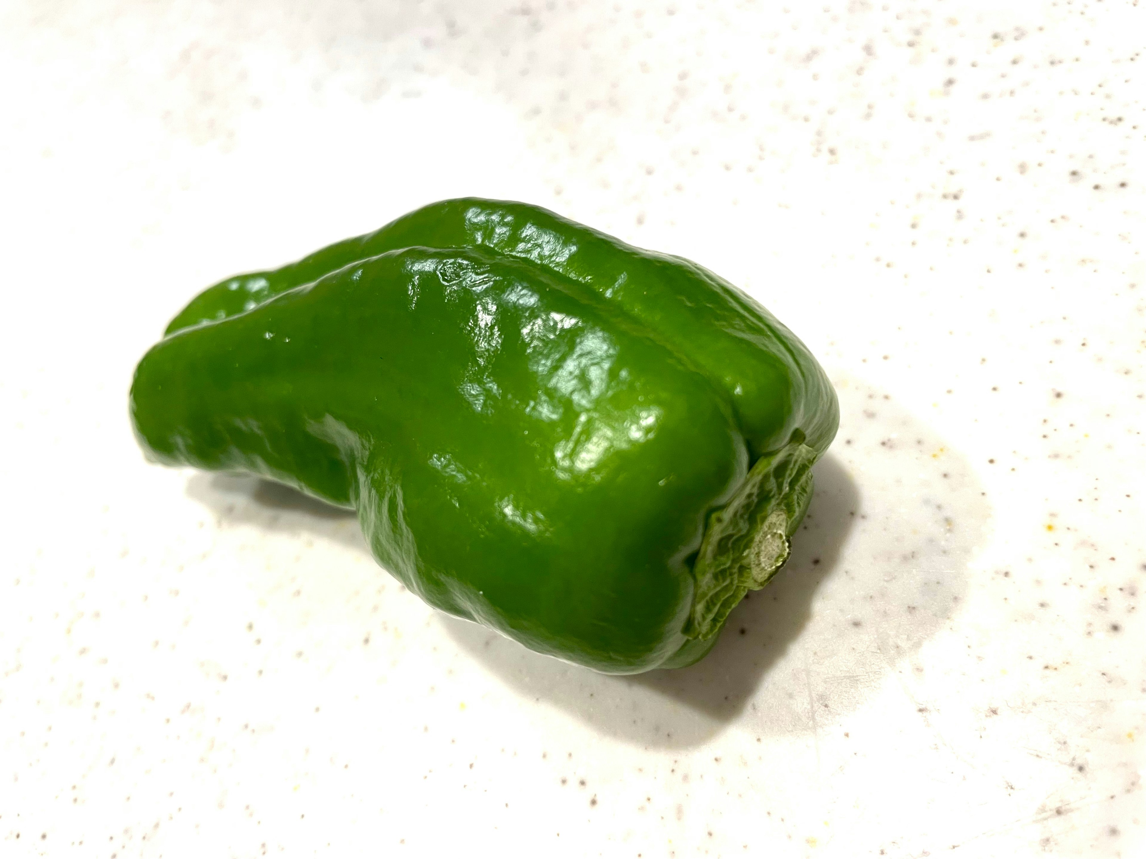 A green bell pepper resting on a table