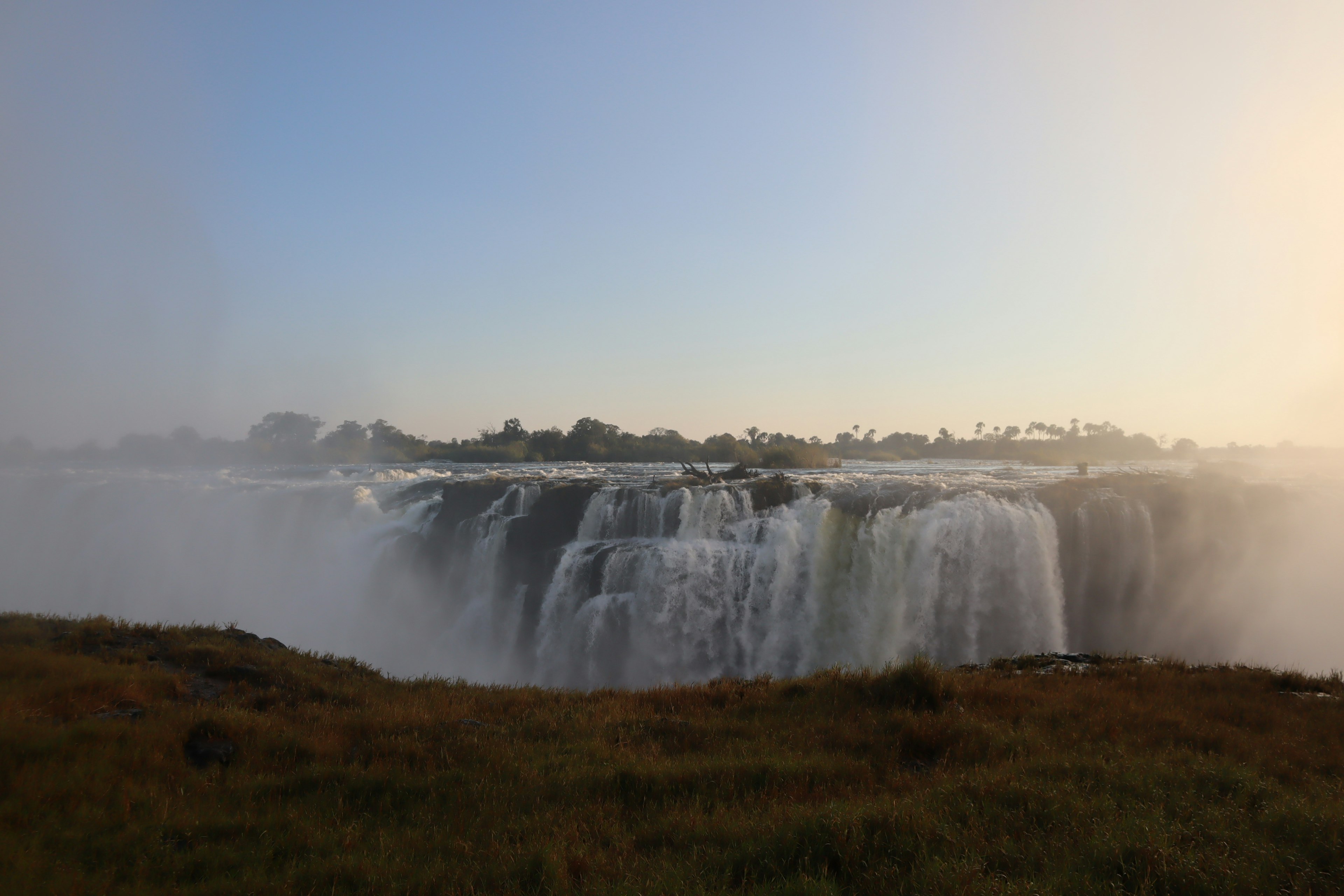 Pemandangan megah Air Terjun Iguazu dengan kabut dan percikan di bawah cahaya senja